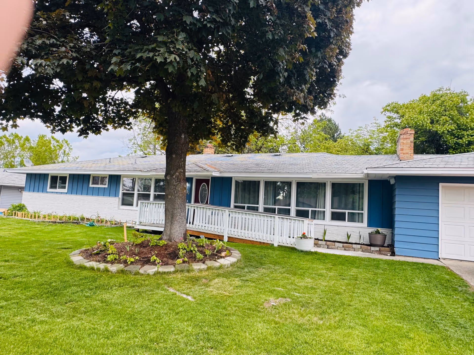 Exterior view of a blue single-story facility with front porch and large tree