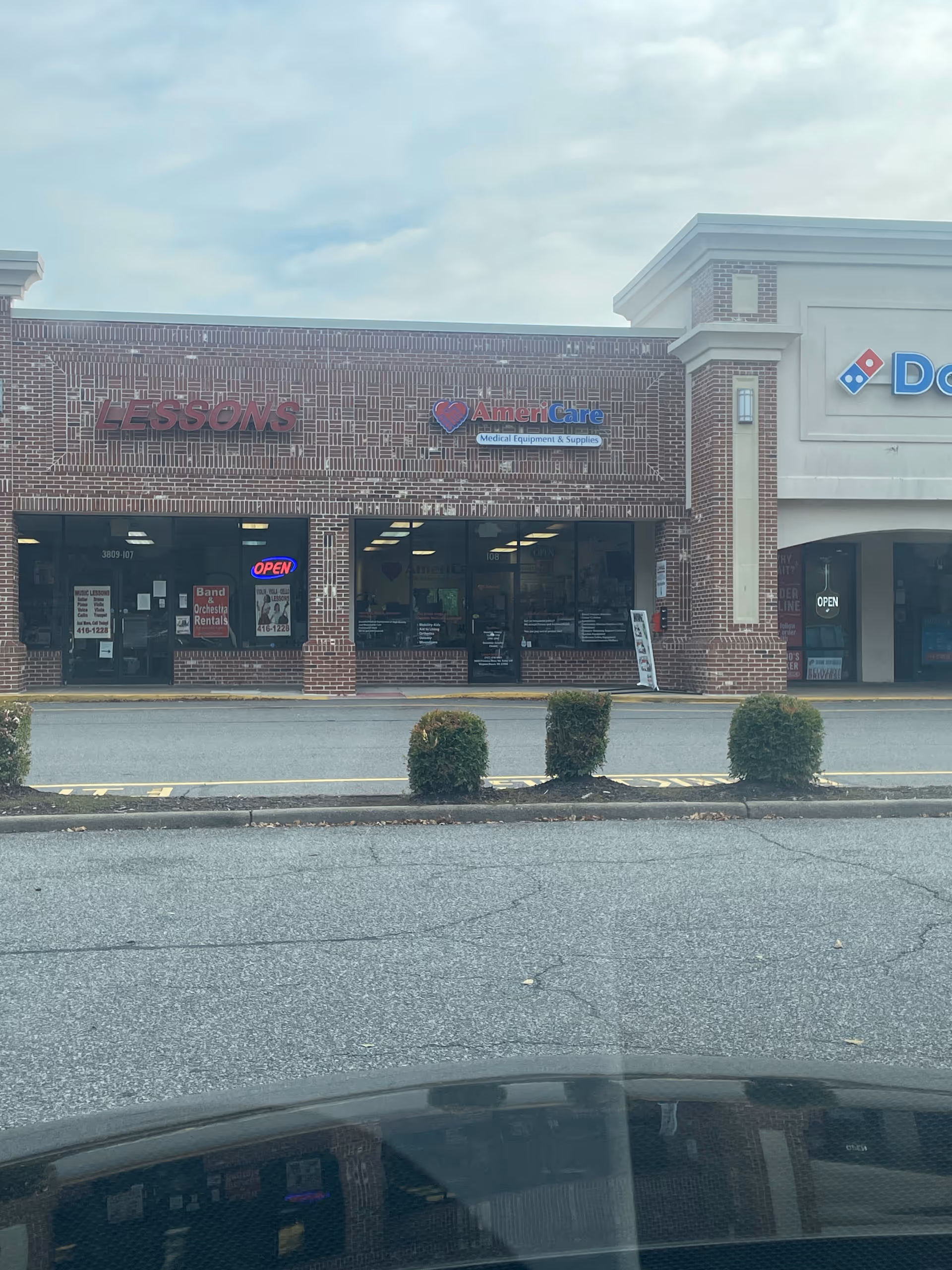 Brick storefront row with Americare Medical Equipment & Supplies sign between Lessons and Domino's.