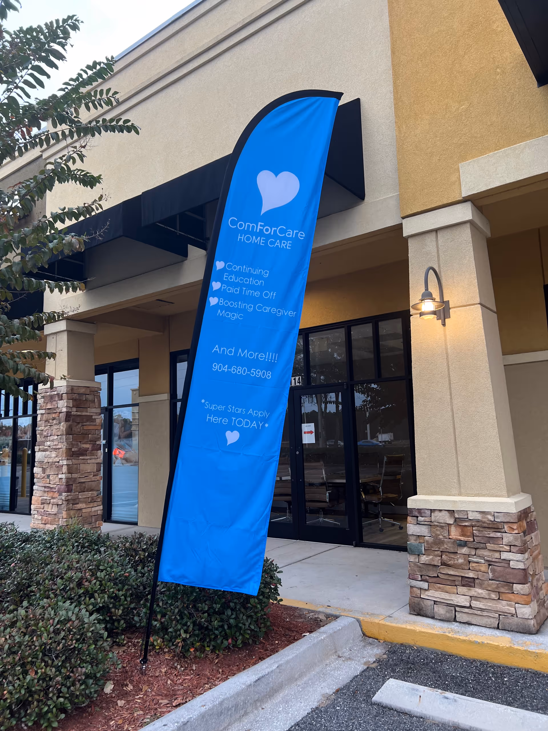 Blue ComForCare Home Care banner outside the facility entrance beside glass doors