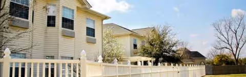 Exterior view of Brookdale Bossier City with beige siding and white railing.