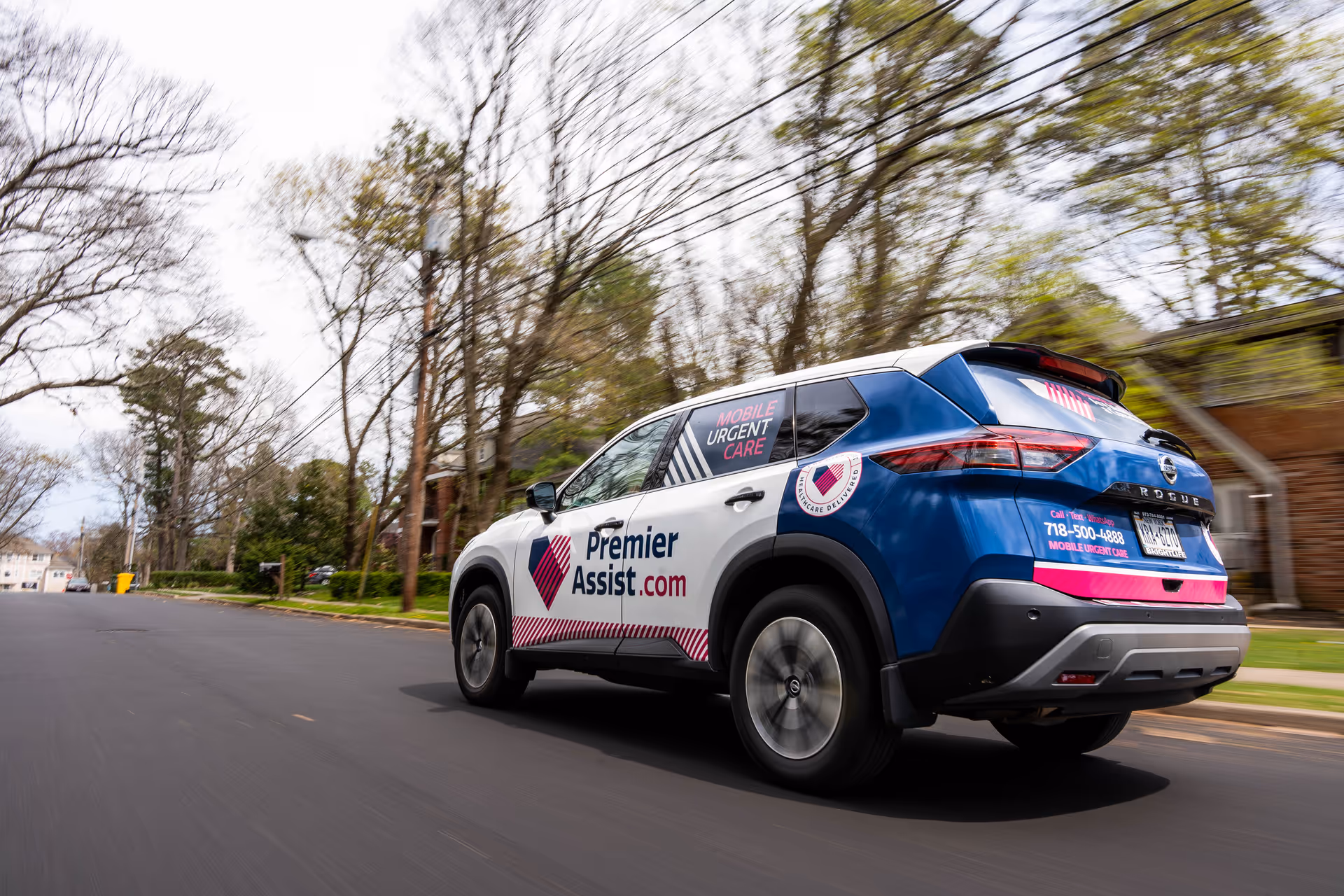 Premier Assist vehicle speeds down a suburban street with leafless trees.