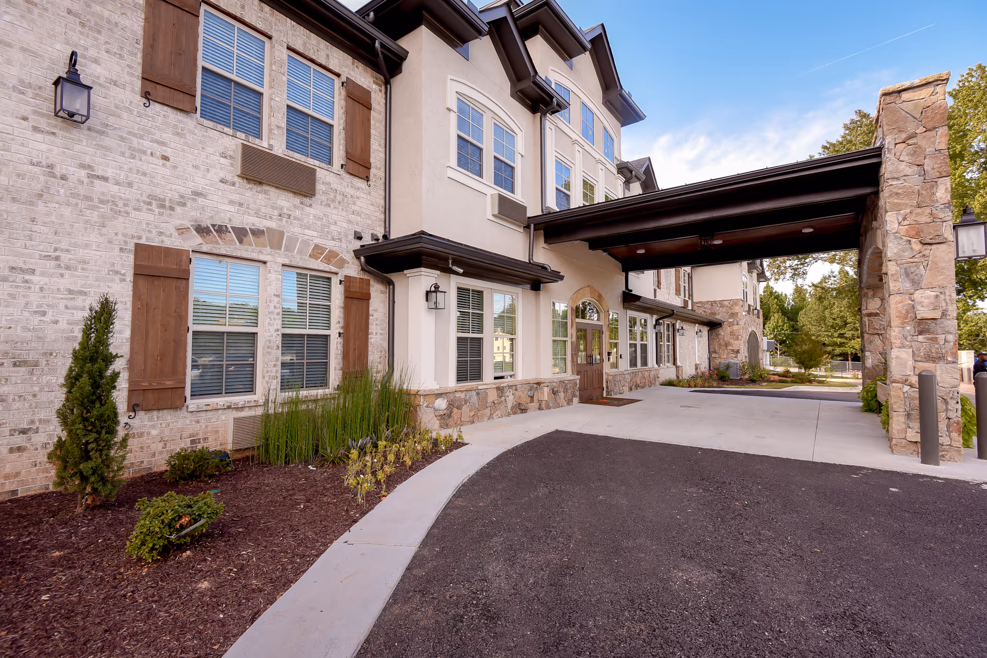 Exterior view of Orchard Senior Living entrance with stone facade and covered driveway.