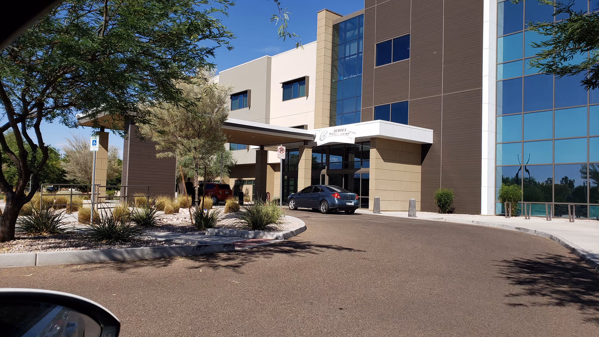 Exterior view of Center at Arrowhead entrance with drive, cars, and landscaping.