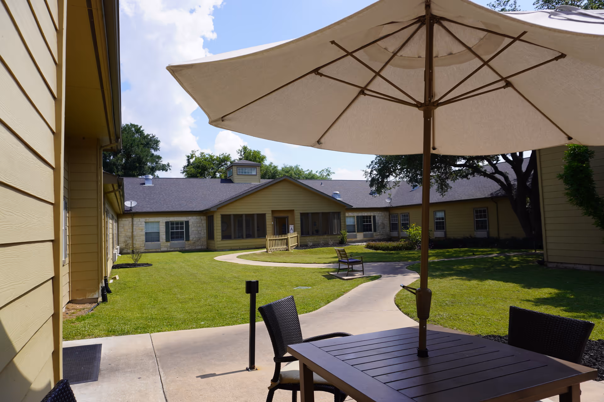 Outdoor courtyard of Sodalis Austin with a table, chairs, and a large umbrella.