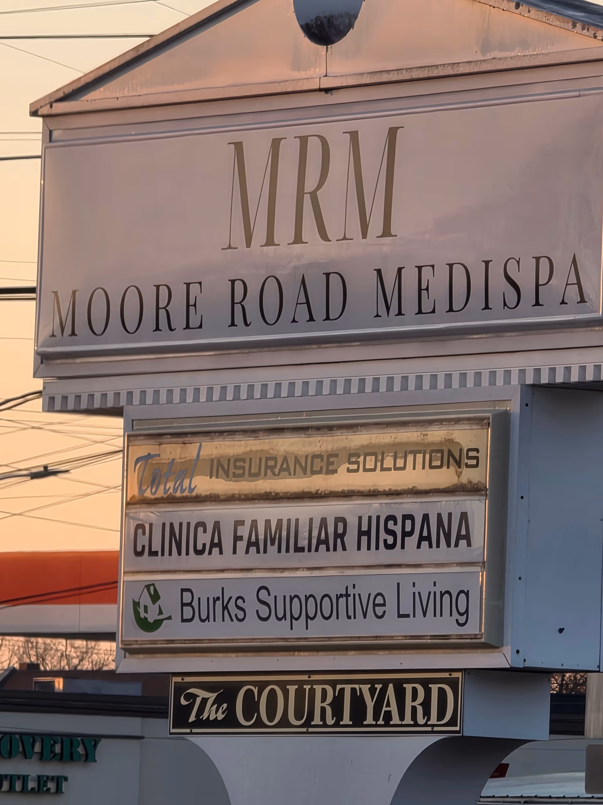 Exterior signboard displaying Burks Supportive Living and other business names on a building.