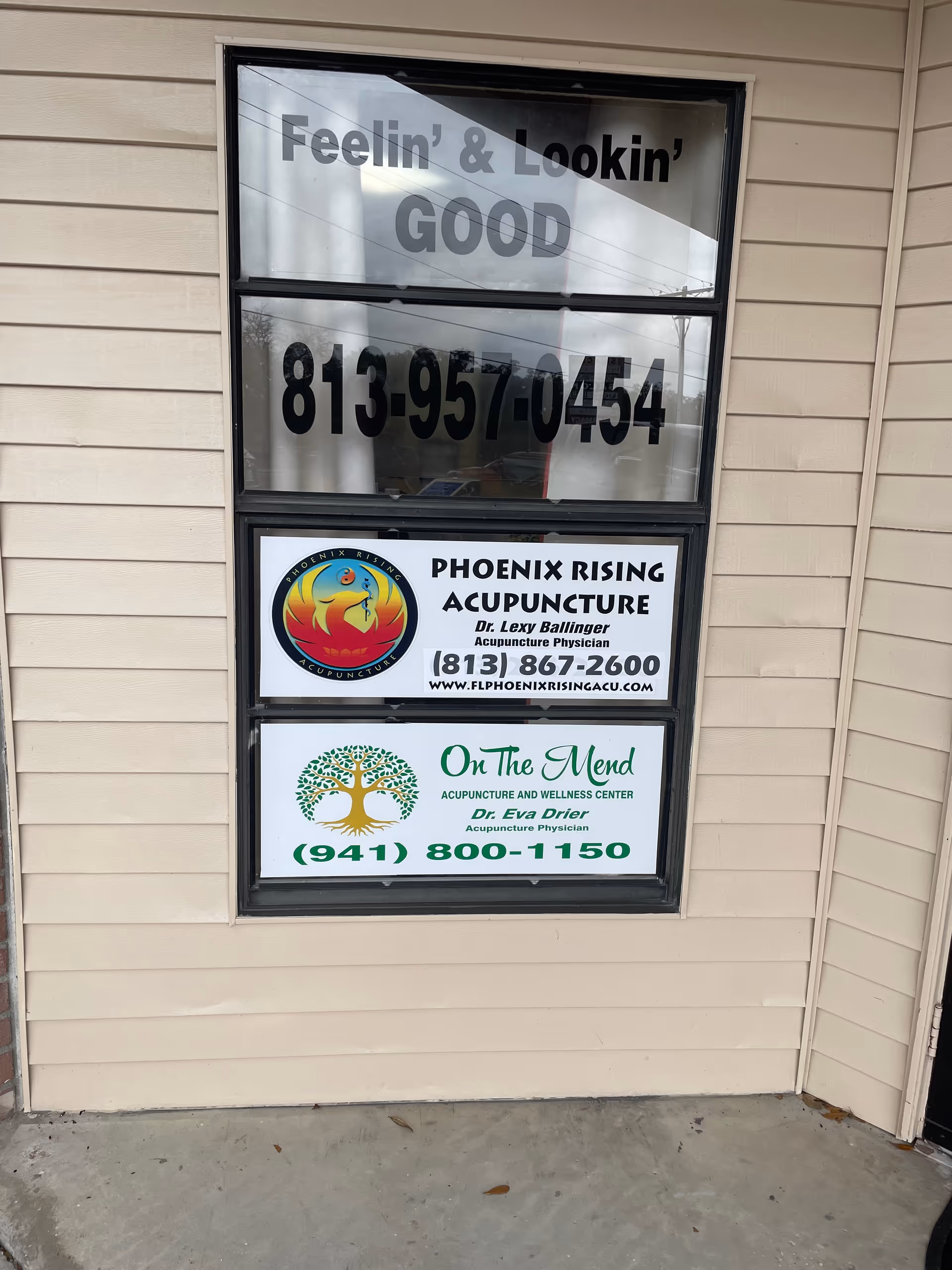 Exterior wall window with Phoenix Rising Acupuncture LLC signs and contact numbers.