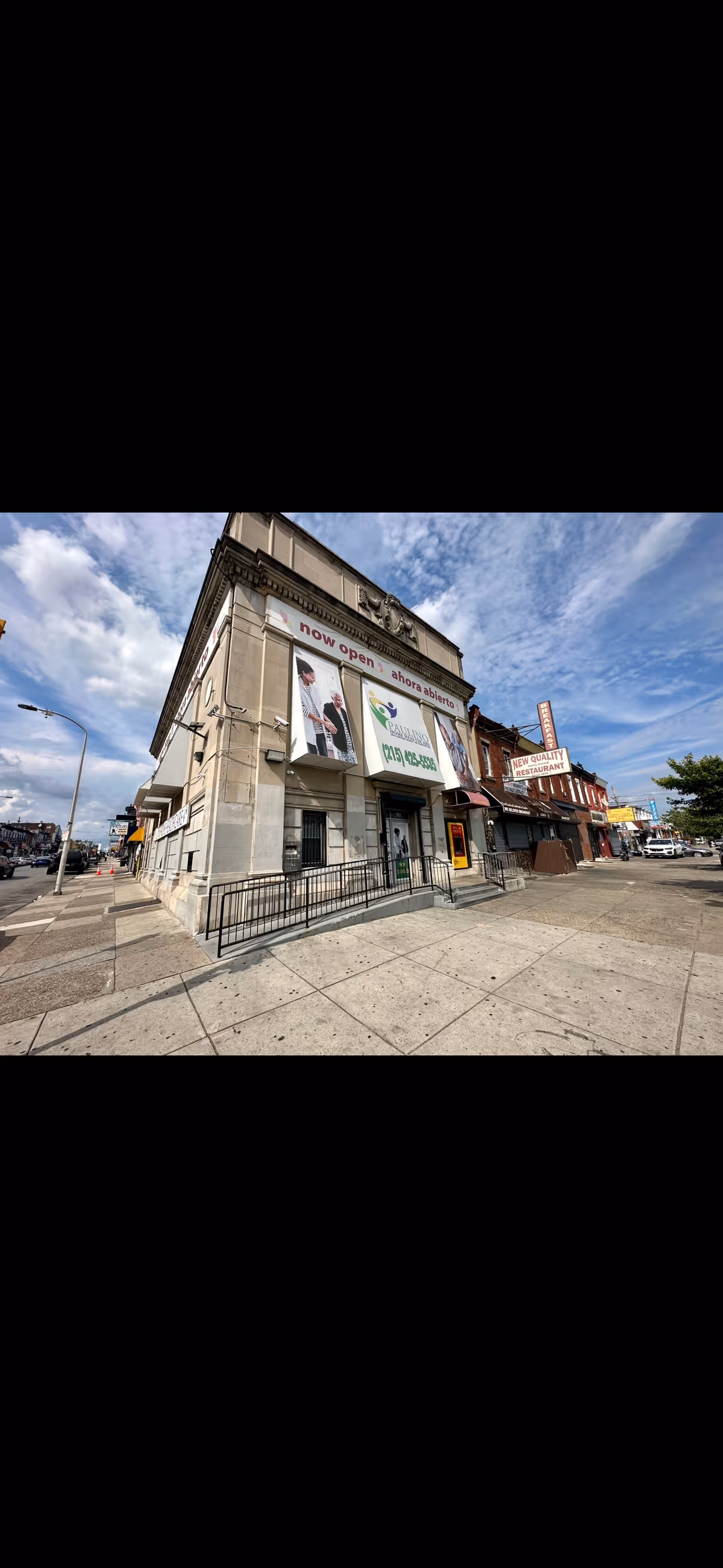 Exterior of a corner building with signs and storefronts along a city street.