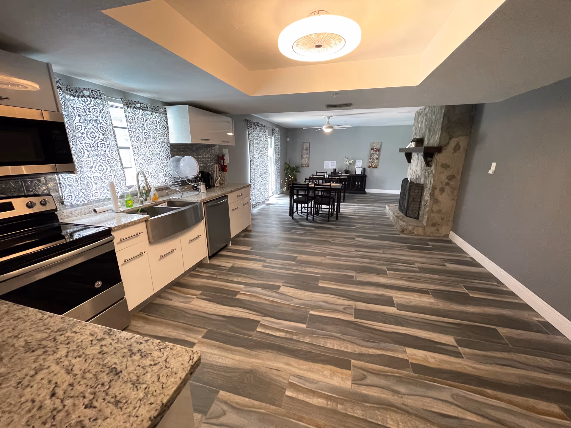 Open-concept kitchen with white cabinets, stainless steel appliances, and a dining area in the background.