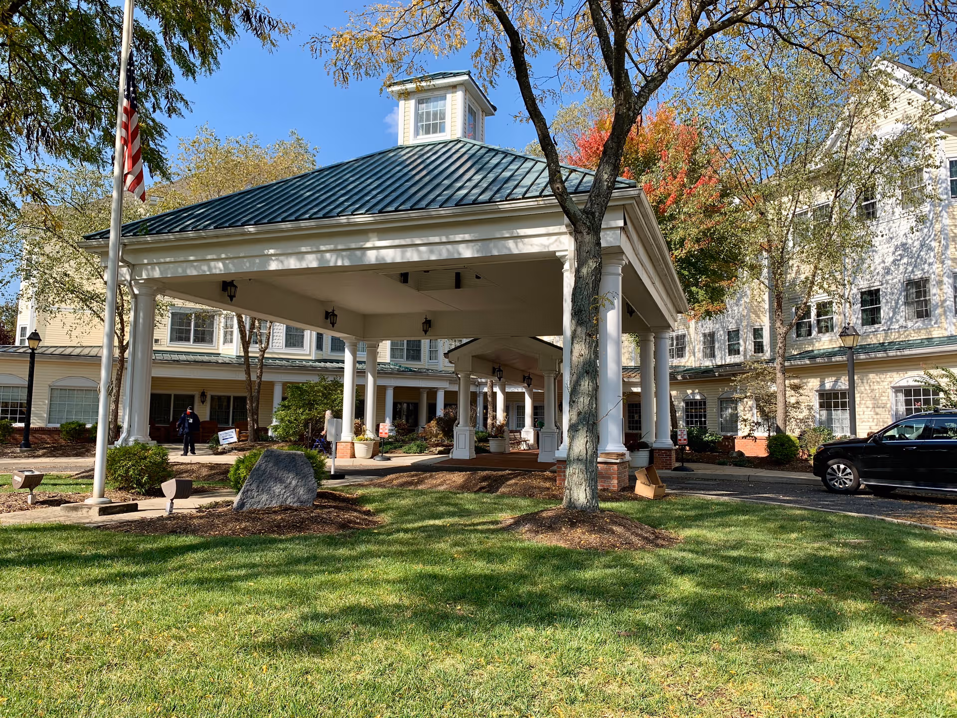 Exterior view of Complete Care at Whispering Woods with a porte-cochère entrance and lawn.