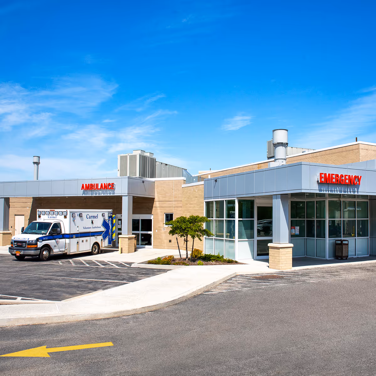 Exterior view of a hospital emergency entrance with an ambulance parked outside.