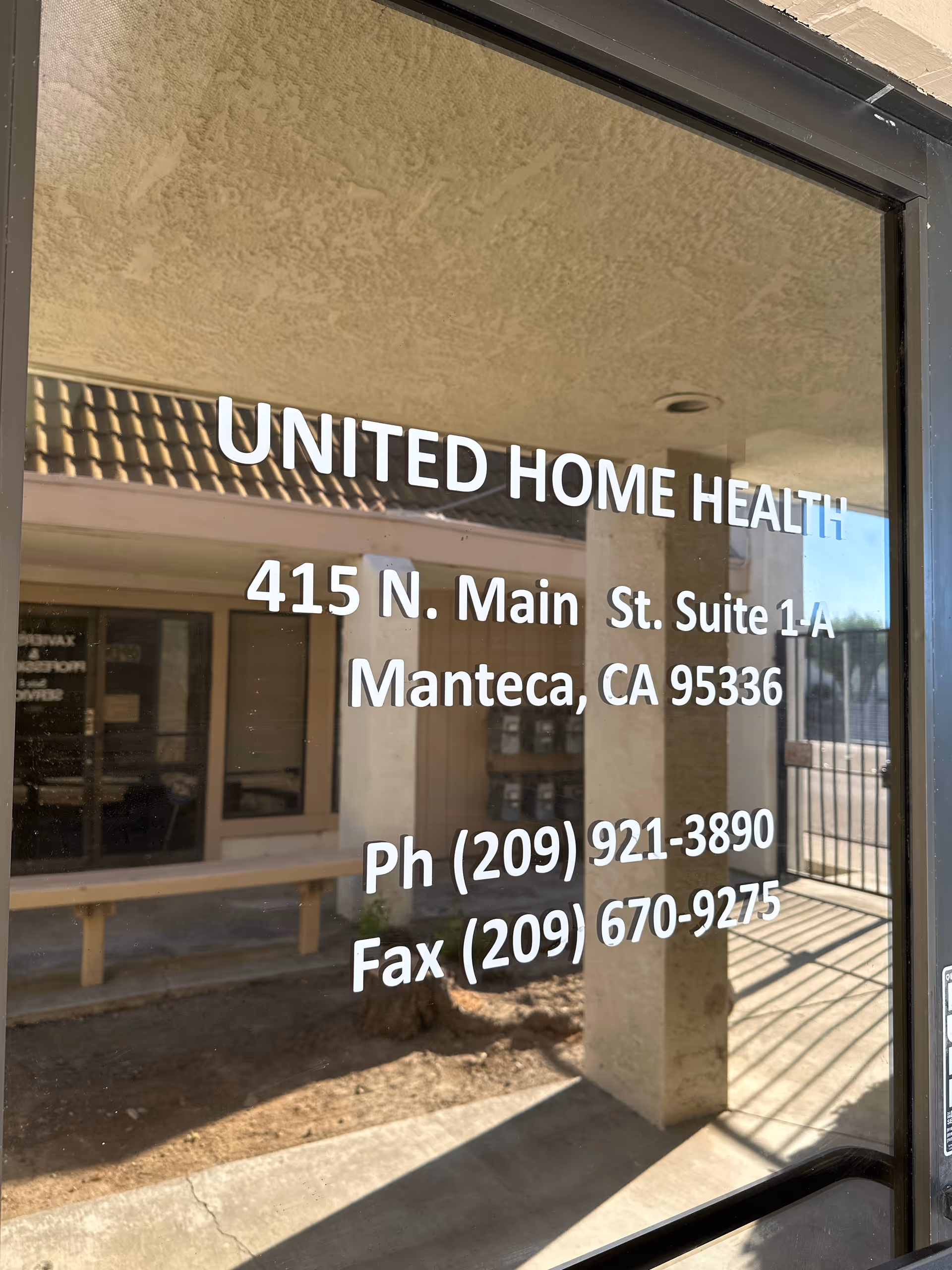 Glass door shows United Home Health sign and address, reflecting the interior.