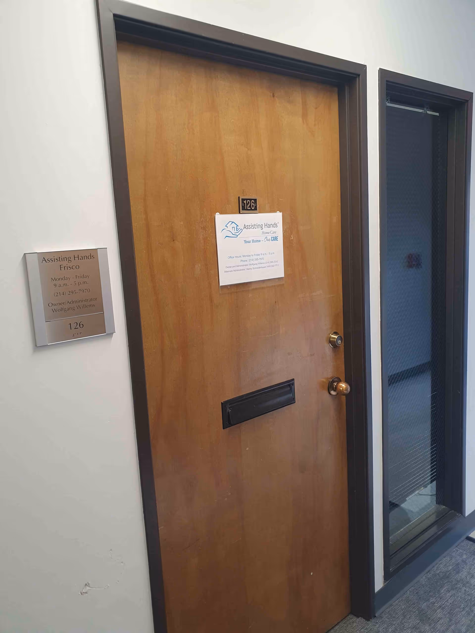 Interior hallway with a wooden door featuring a mail slot and plaque.