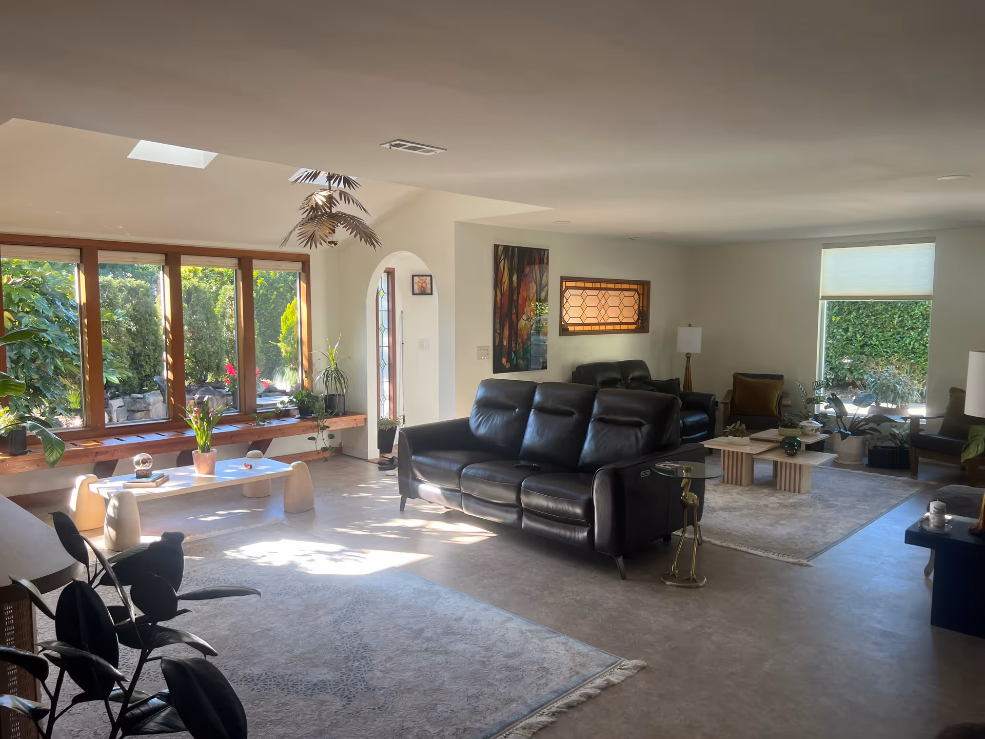 Spacious living room in a senior home with leather sofas, plants, and ample natural light.