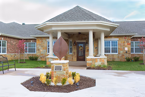 Front entrance of Silverado Lee's Summit Memory Care Community with stone pillars and landscaped courtyard