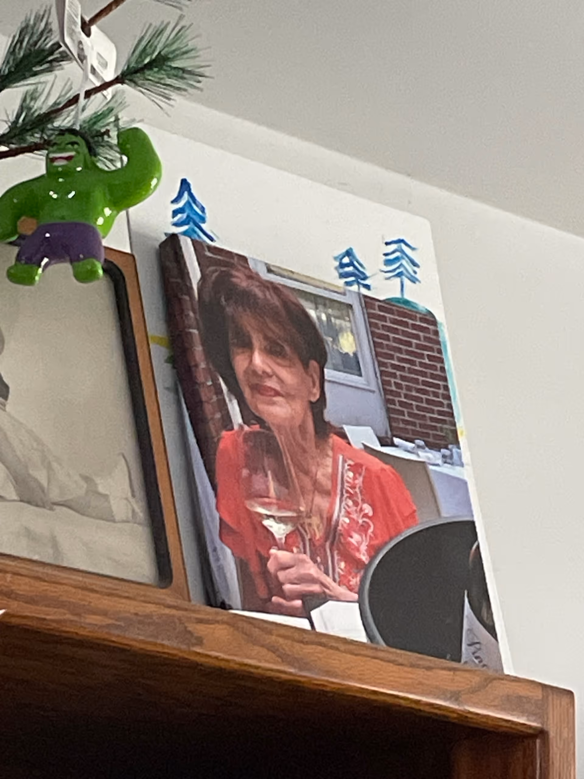 Framed photo of a woman holding a wine glass on a wooden shelf indoors.