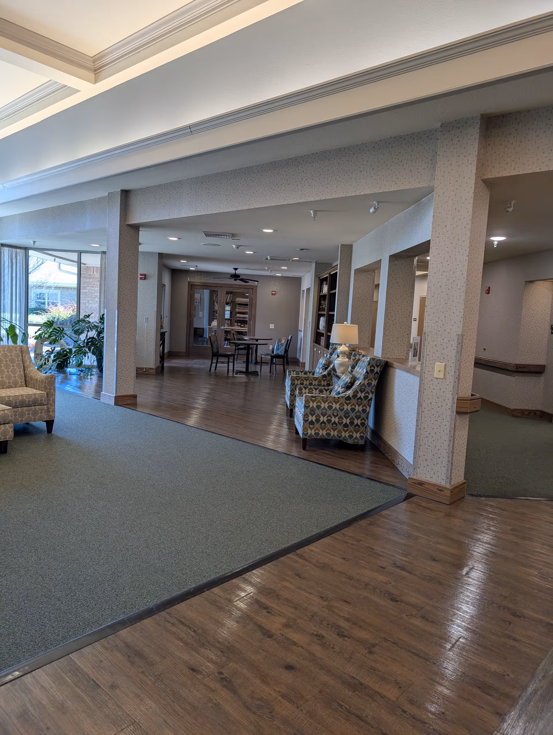 Interior senior living lobby with seating, tables, and open walkways.