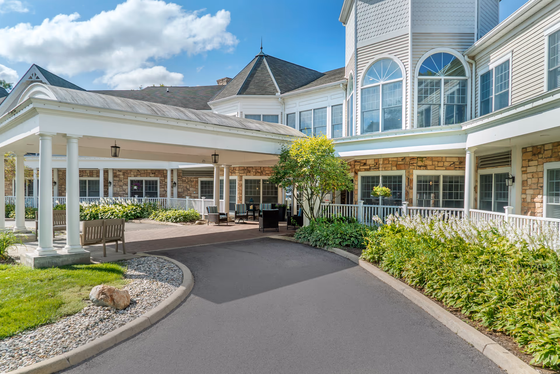 Bright building entrance with covered drop-off, columns, and landscaped walkway at Brookdale Ann Arbor