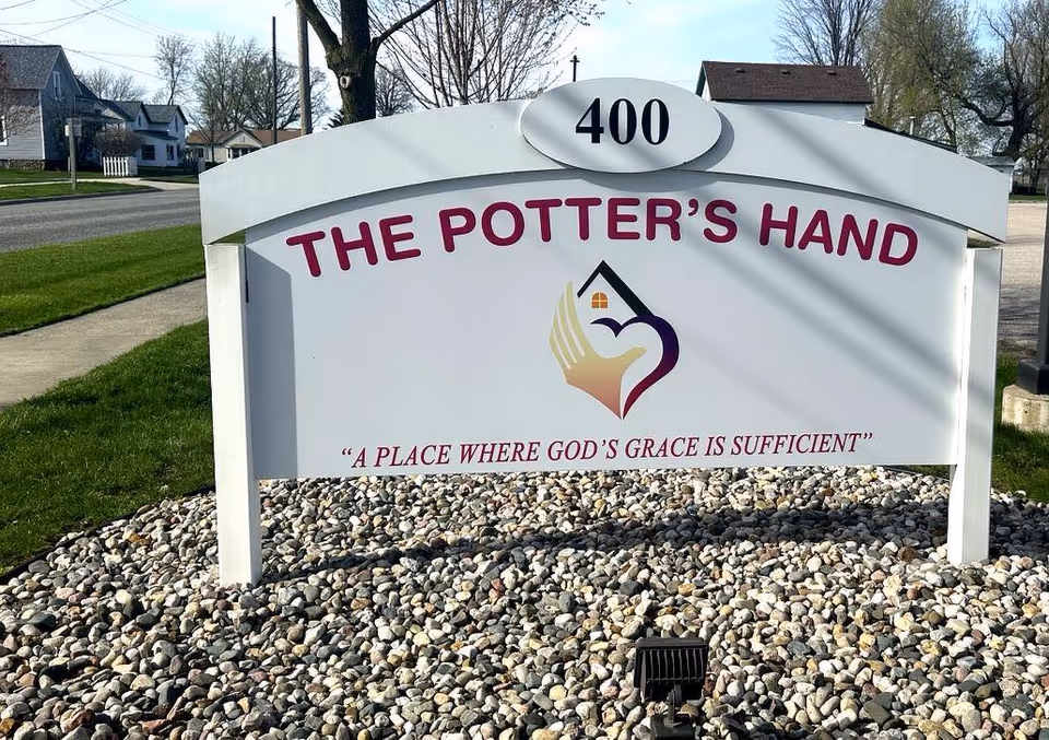 Outdoor freestanding sign reading The Potter's Hand with address 400, set on stone landscaping