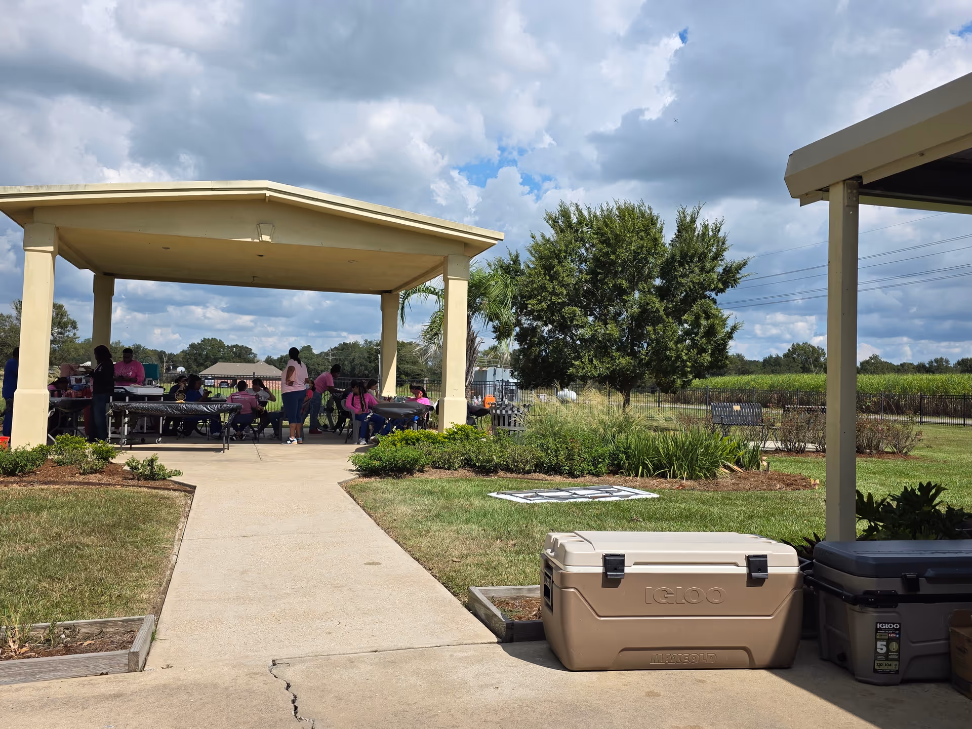 Outdoor pavilion with residents and staff seated at tables beneath a covered shelter.