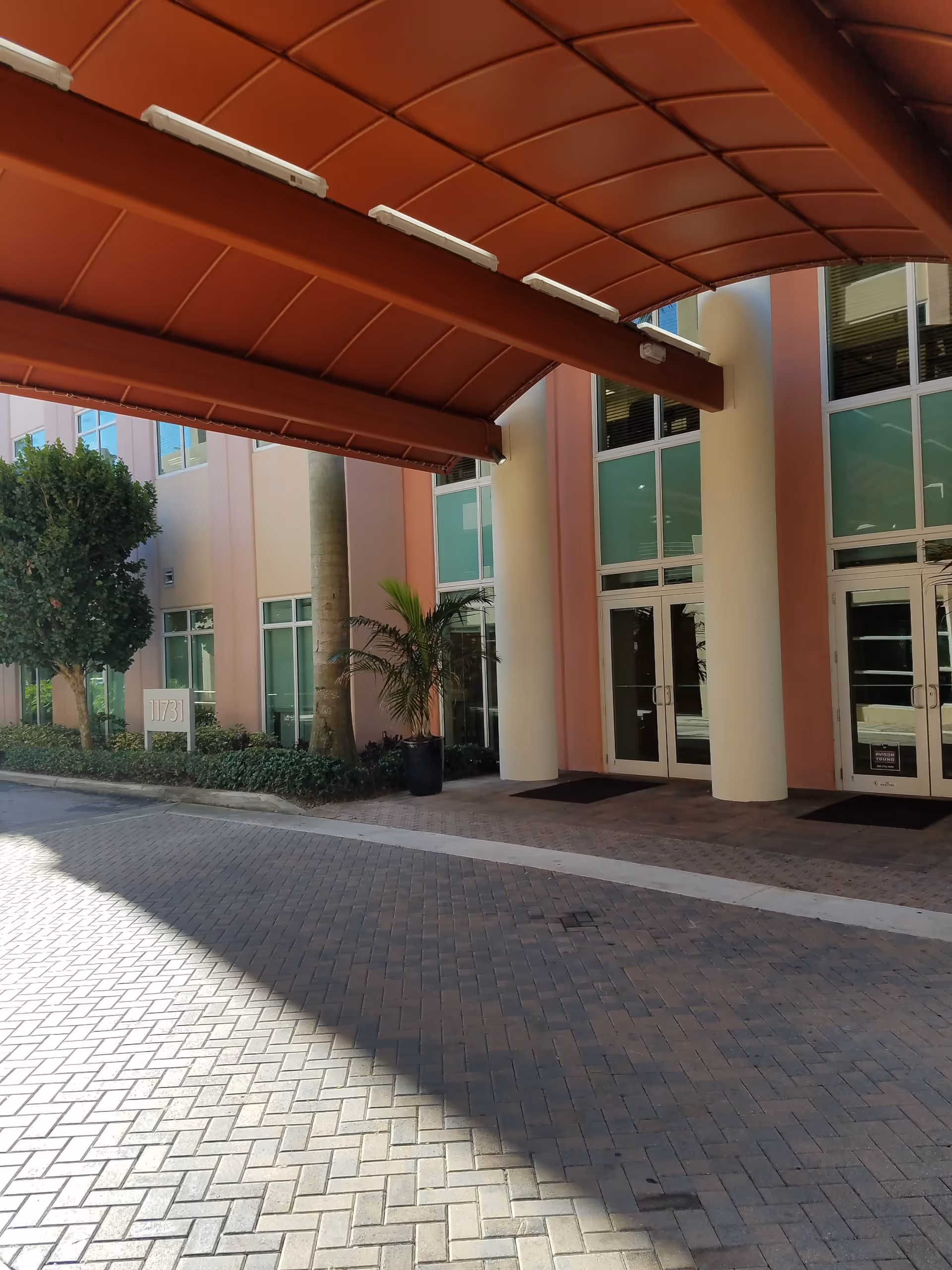 Exterior view of a senior living facility entrance with a red canopy and glass doors.