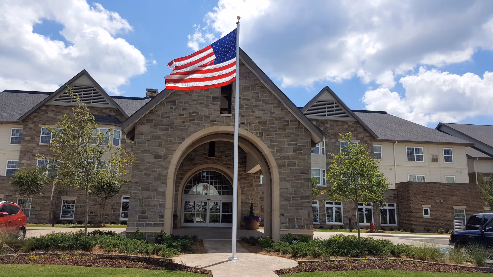 Exterior view of Cahaba Ridge Retirement Community with flag and arched entrance.