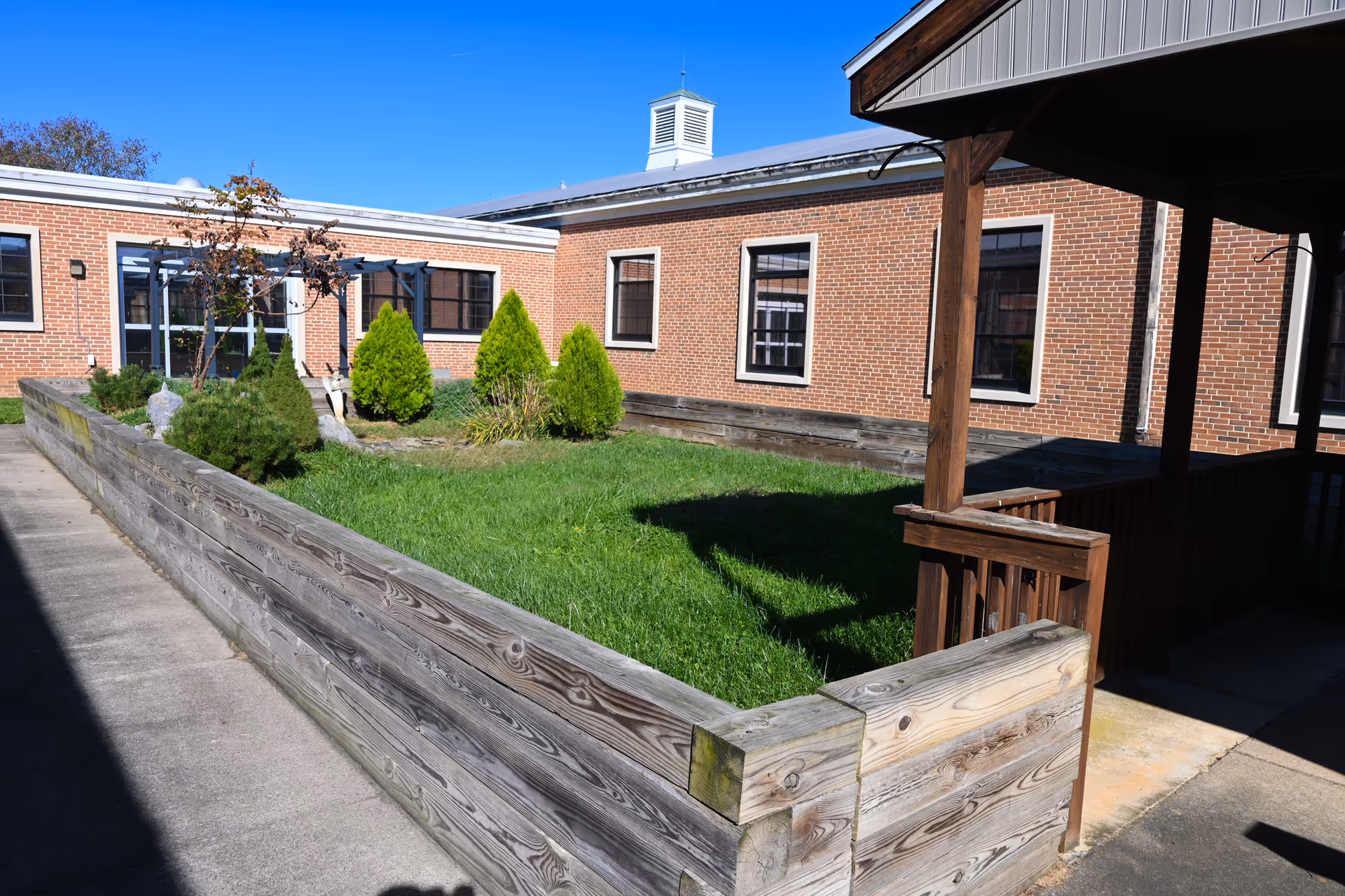Exterior view of Laurel Lakes facility with brick walls, lawn, and wooden planters.