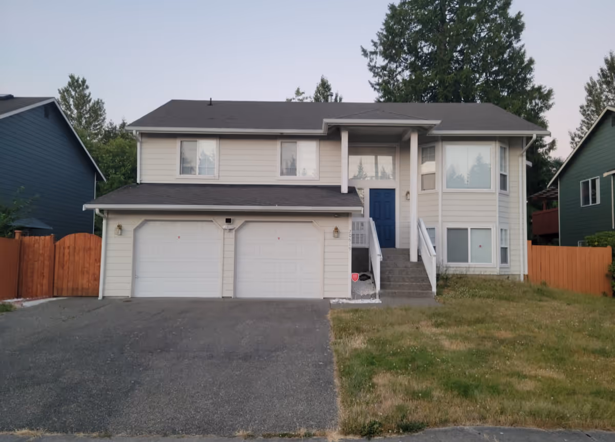 Two-story beige house with attached garage and blue front door.