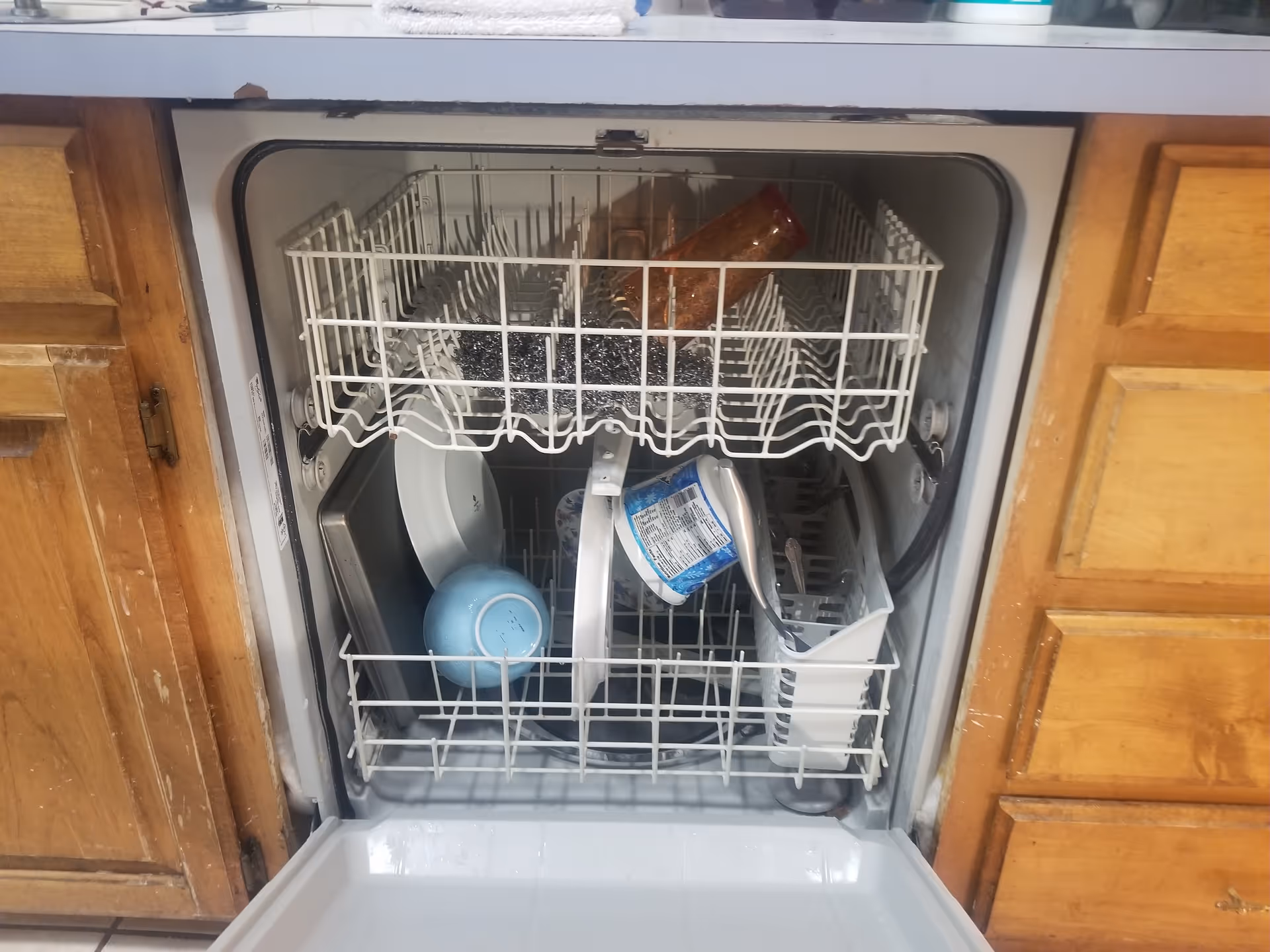 Open dishwasher loaded with dishes inside a wooden kitchen.