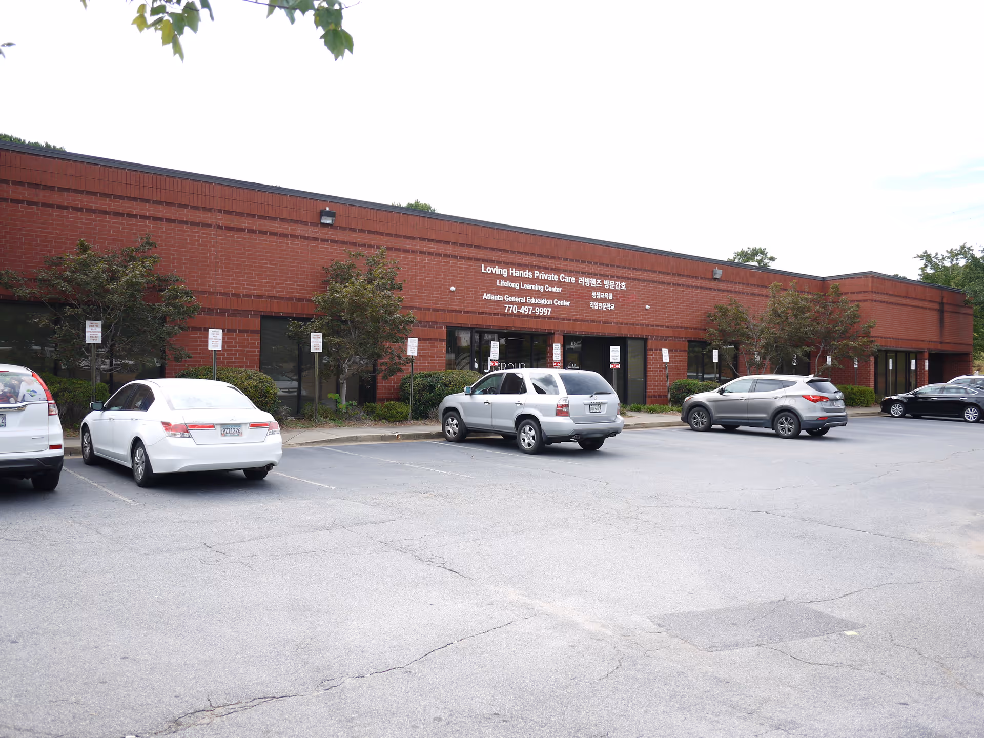 Brick, single-story facility with a parking lot and signage for Loving Hands Private Care.