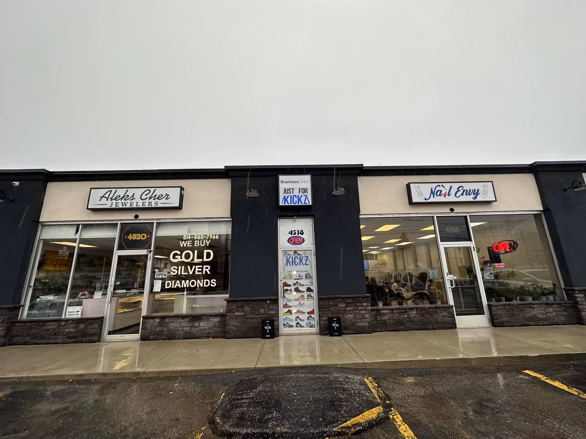 Exterior storefronts of a strip mall, including jewelry store and nail salon.
