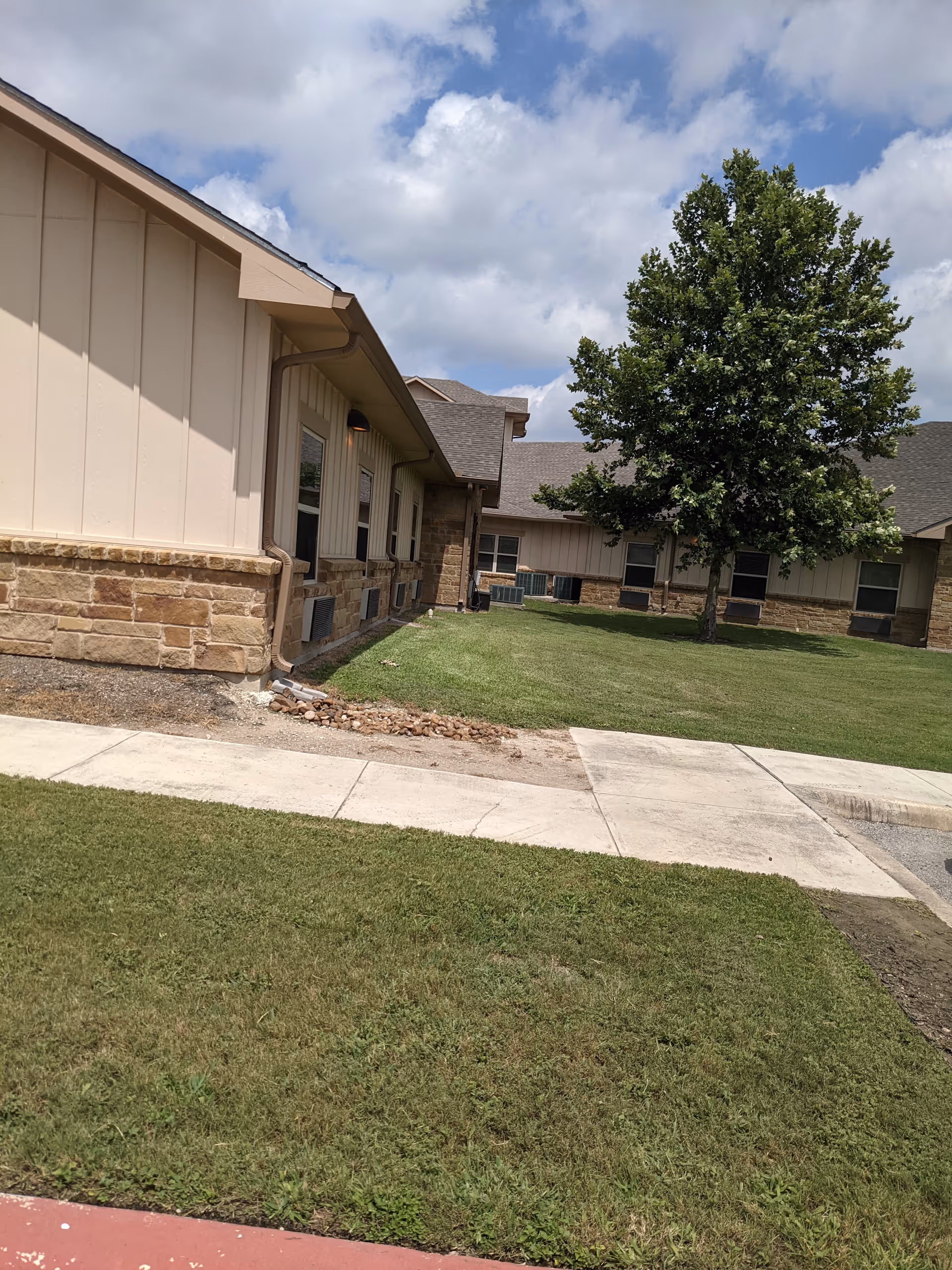 Exterior view of Lakeside Nursing and Rehabilitation Center with sidewalk and tree.