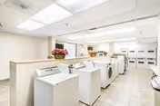 Bright communal laundry room with multiple washers and dryers at Thomas F Williams Court Apts.
