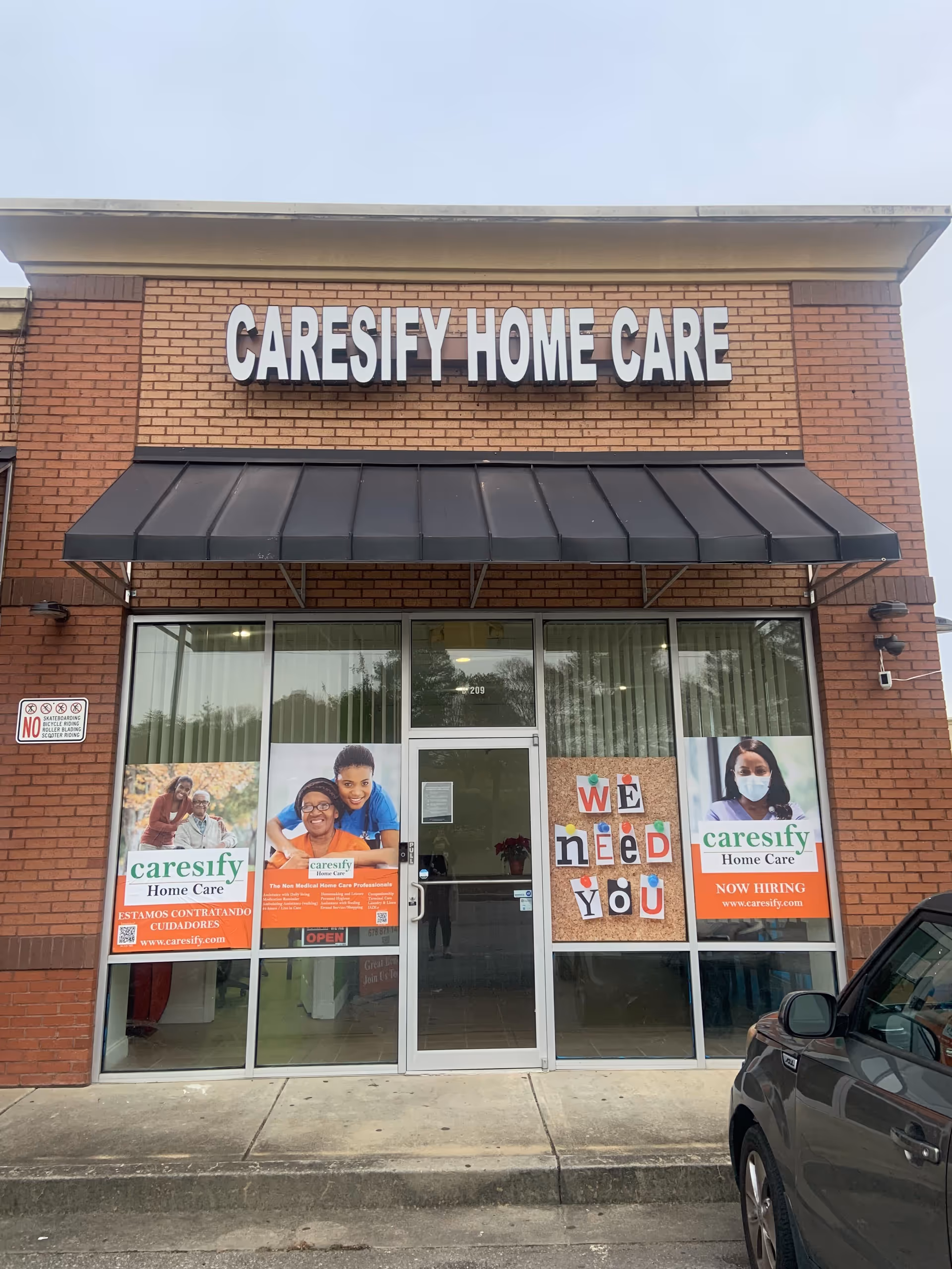 Brick storefront with CARESIFY HOME CARE sign and posters on glass entry doors.