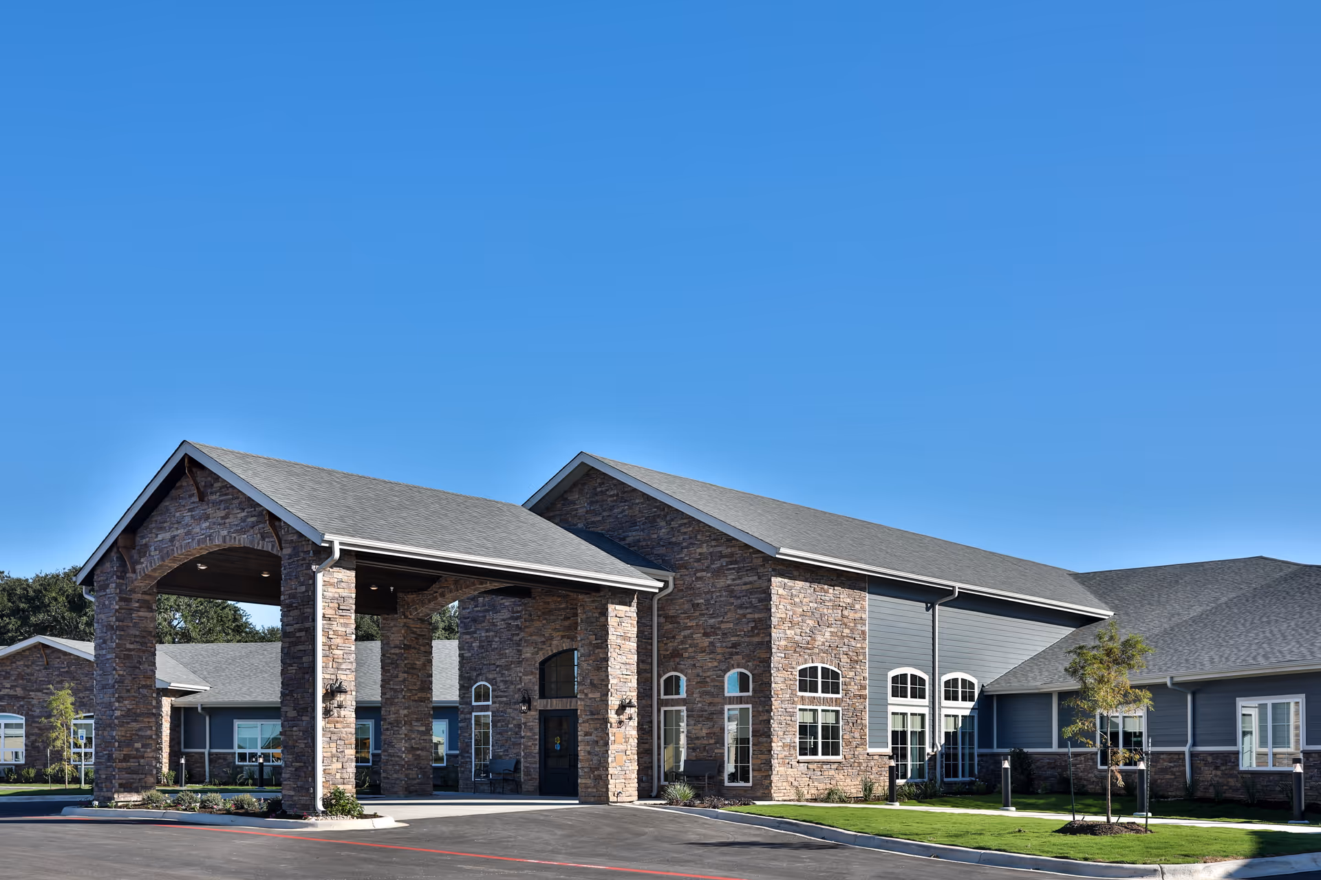 Stone entrance of Towers Nursing Home with a covered drop-off area and blue sky.