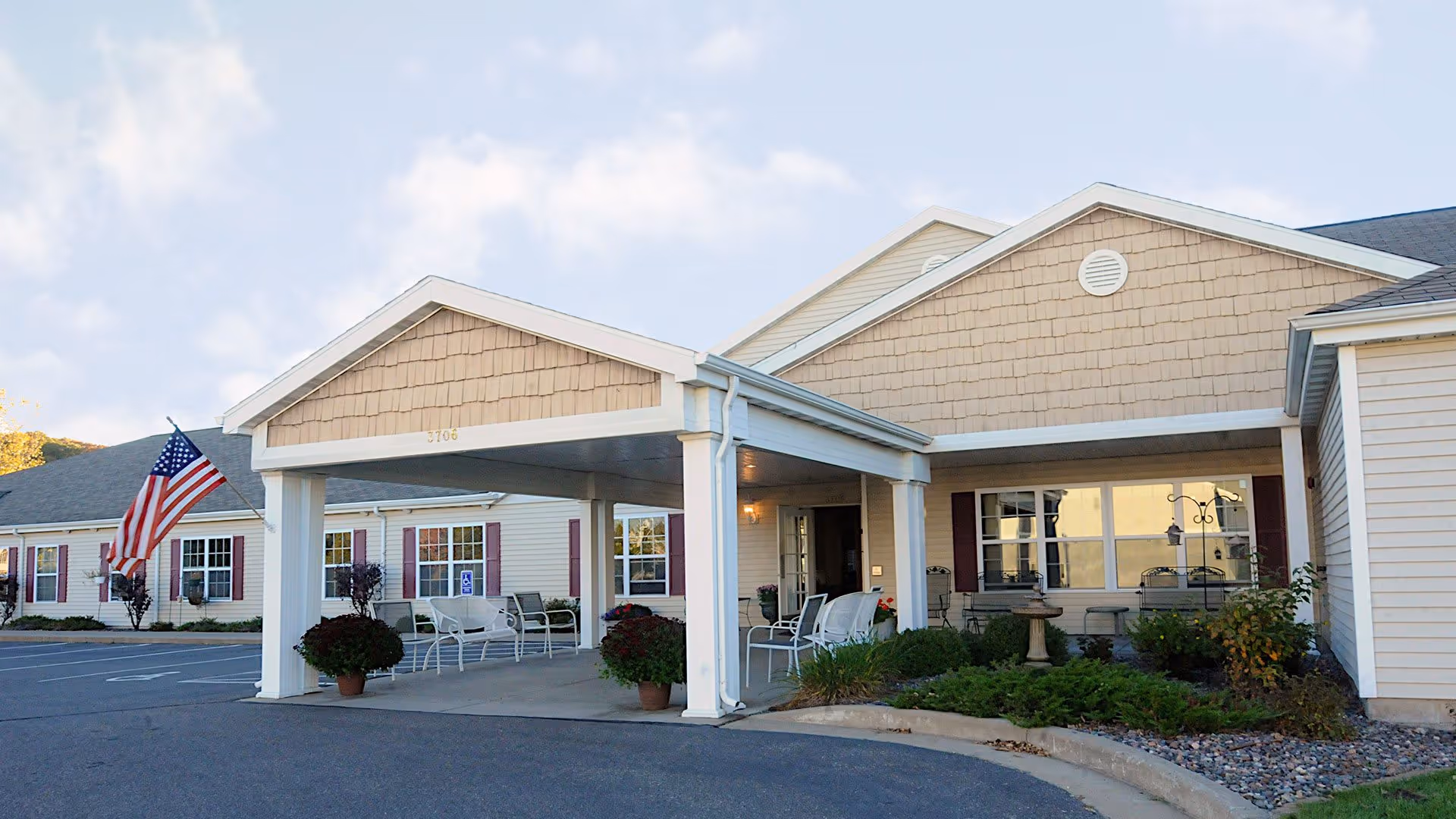 Front exterior of Heritage Senior Living at Oakwood Hills with entrance canopy and seating.
