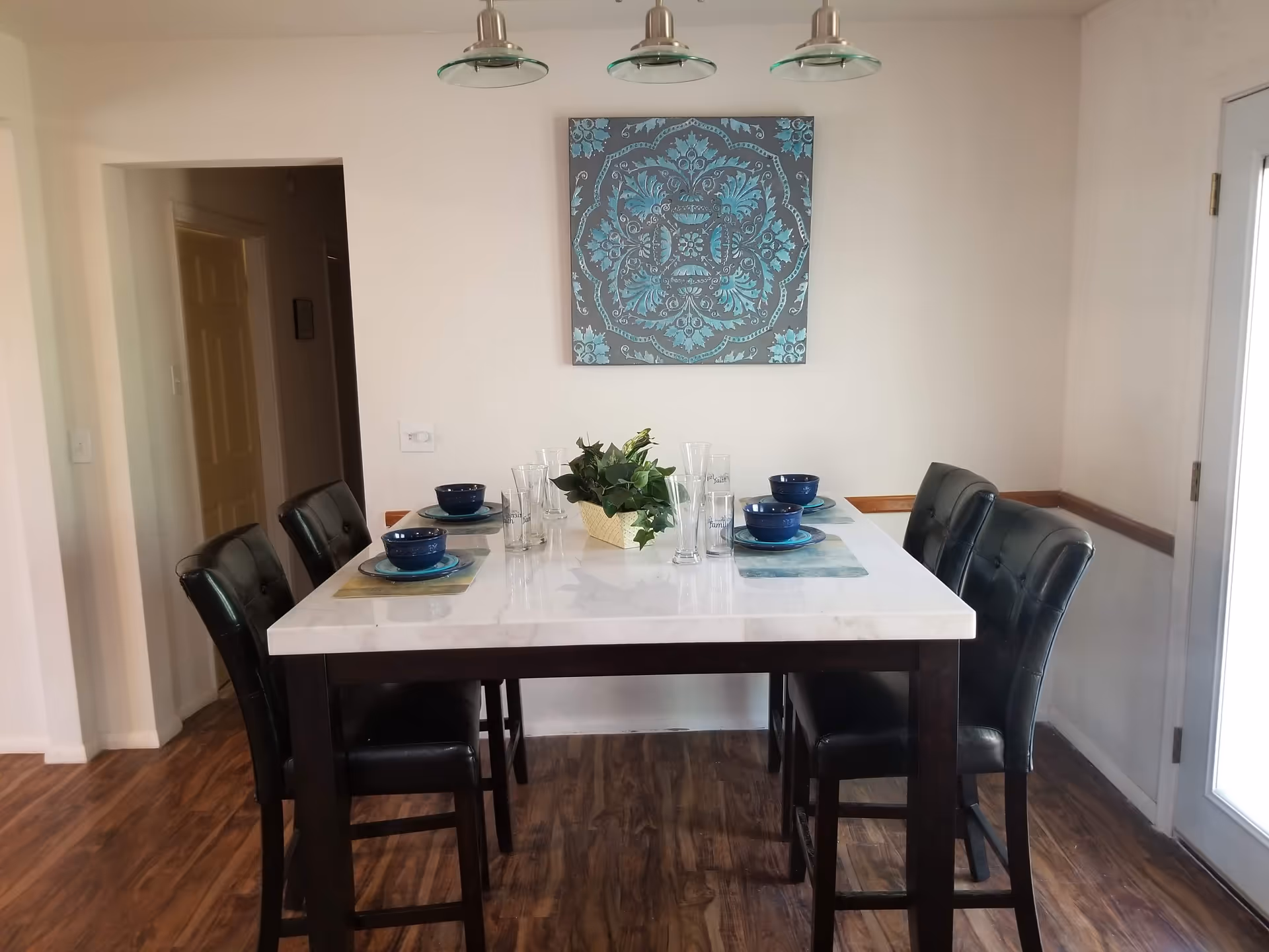 A modern dining room with a white table, dark chairs, and blue bowls.