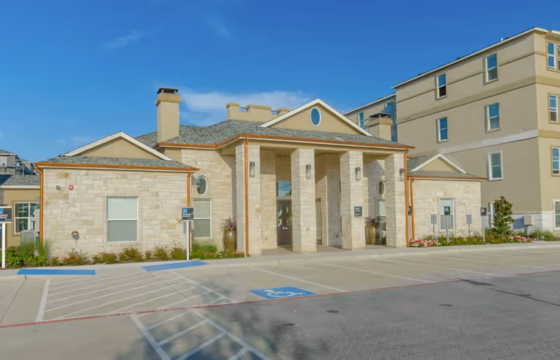 Stone-front senior living entrance with columns, drive, and handicap parking at Winslow Commons.