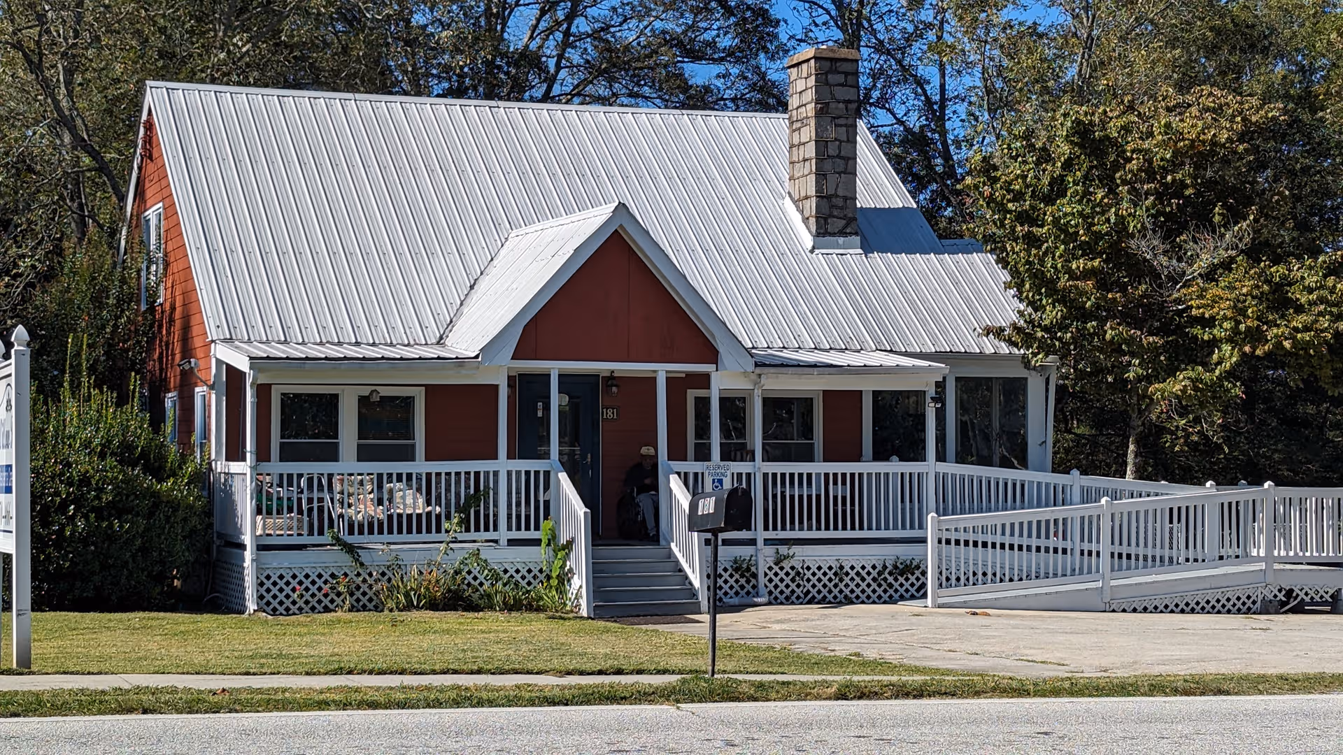 Red single-story senior living facility with white porch and ramp.