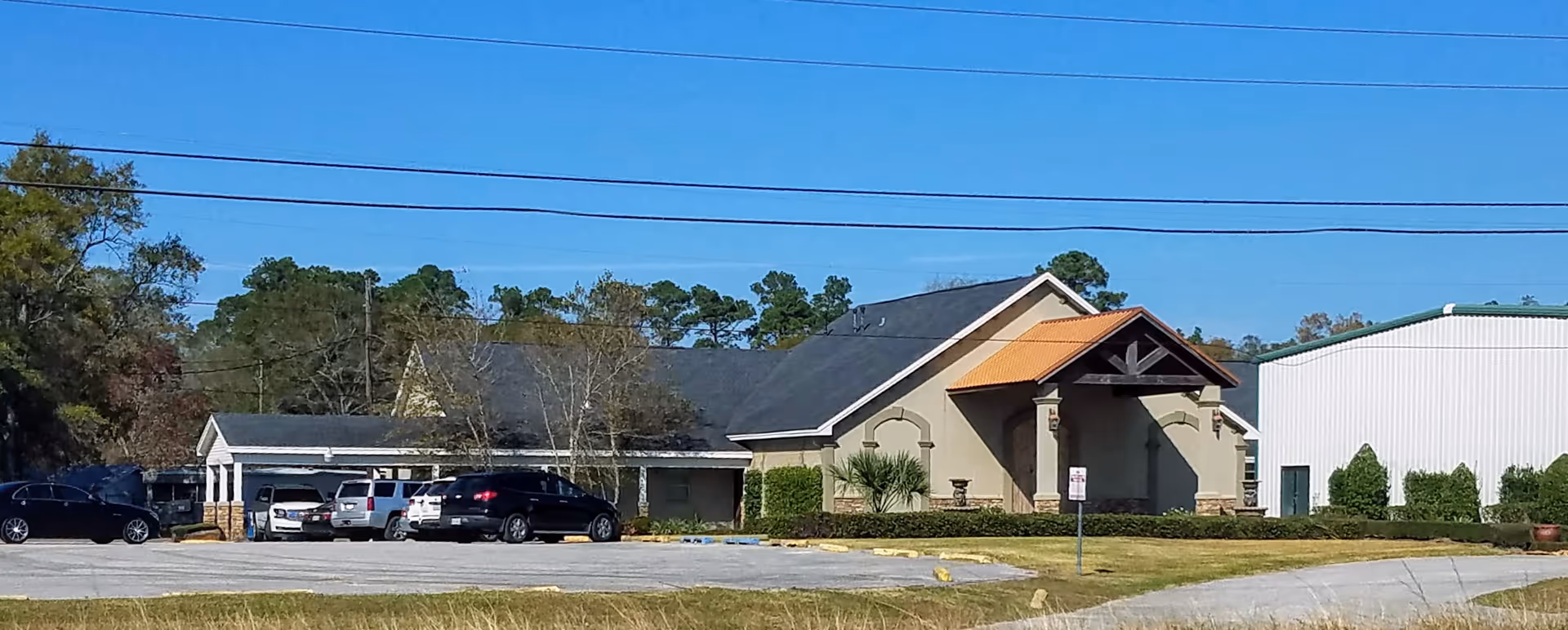 Exterior view of a Texas Total Care senior facility with parking lot and cars.