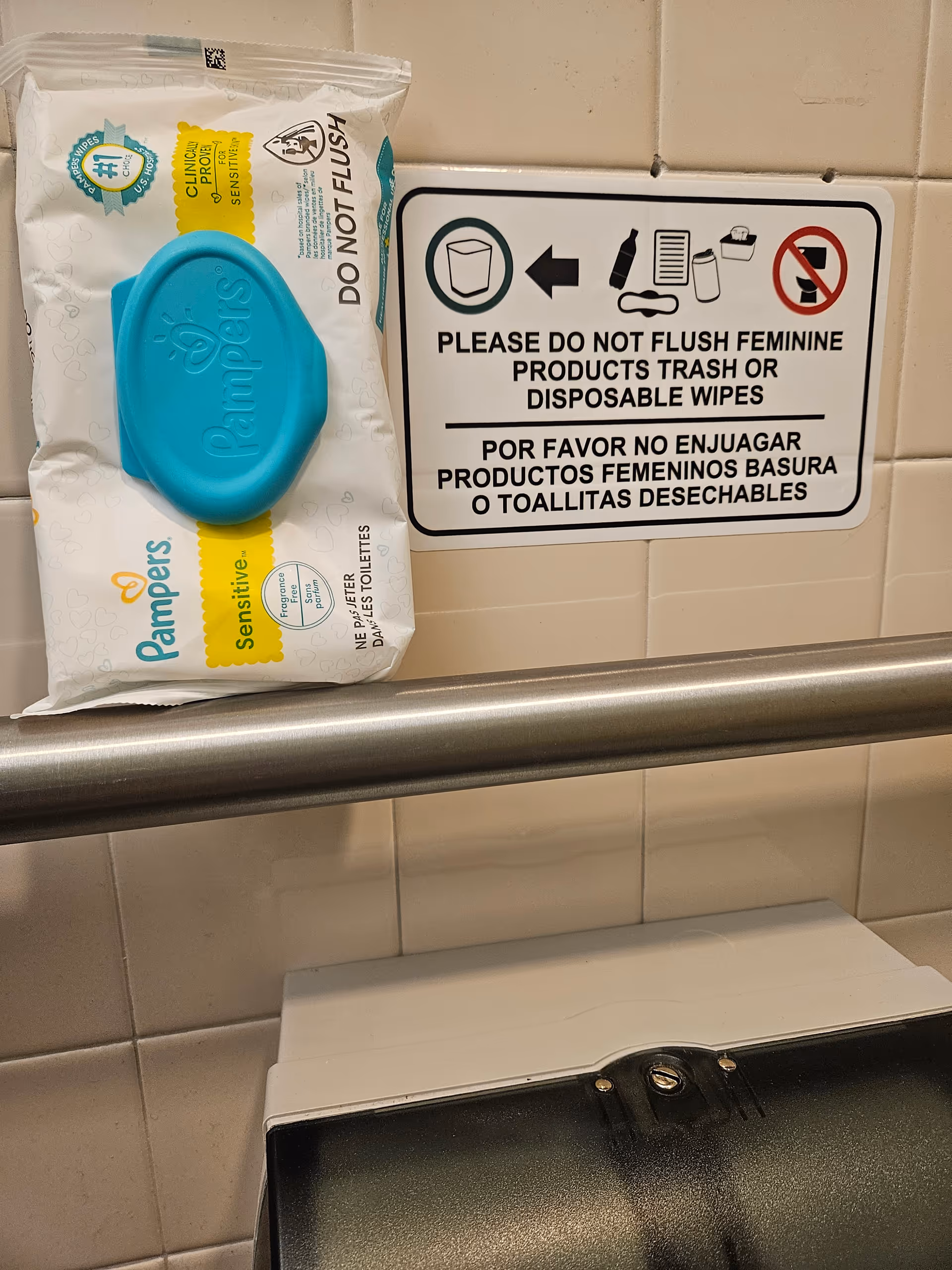 Bathroom wall with a 'DO NOT FLUSH' sign and a Pampers Sensitive wipes package.