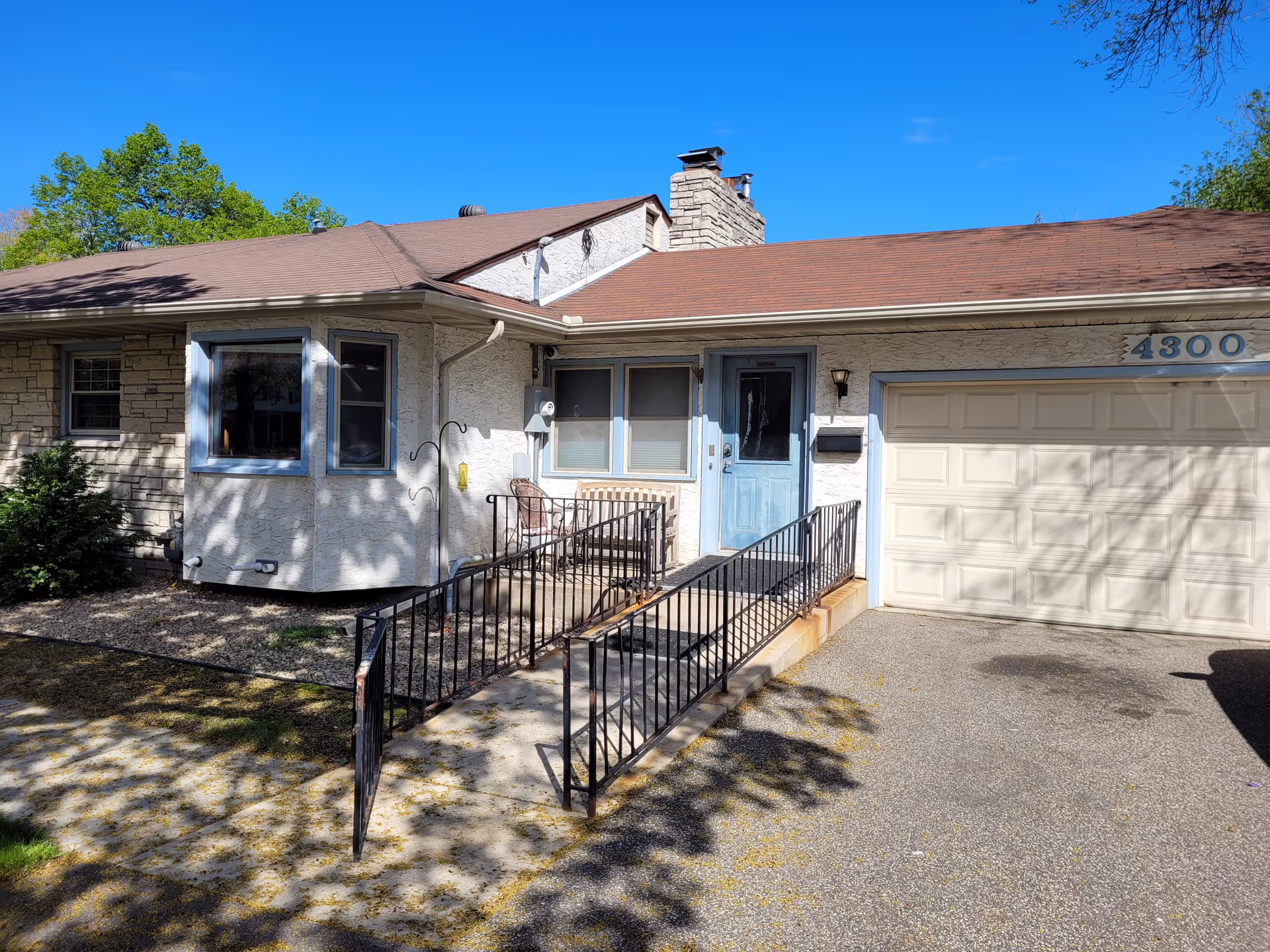Exterior of a single-story senior living home with blue entry door and ramp.