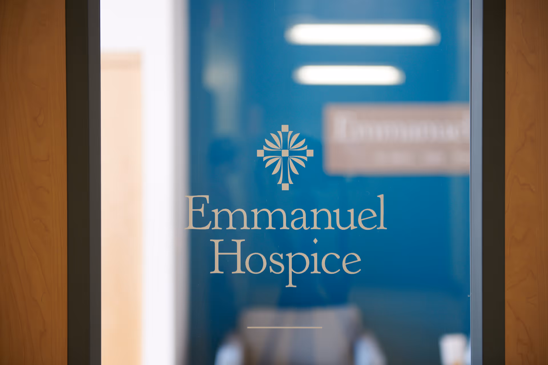 Blue glass door displays Emmanuel Hospice logo and text.