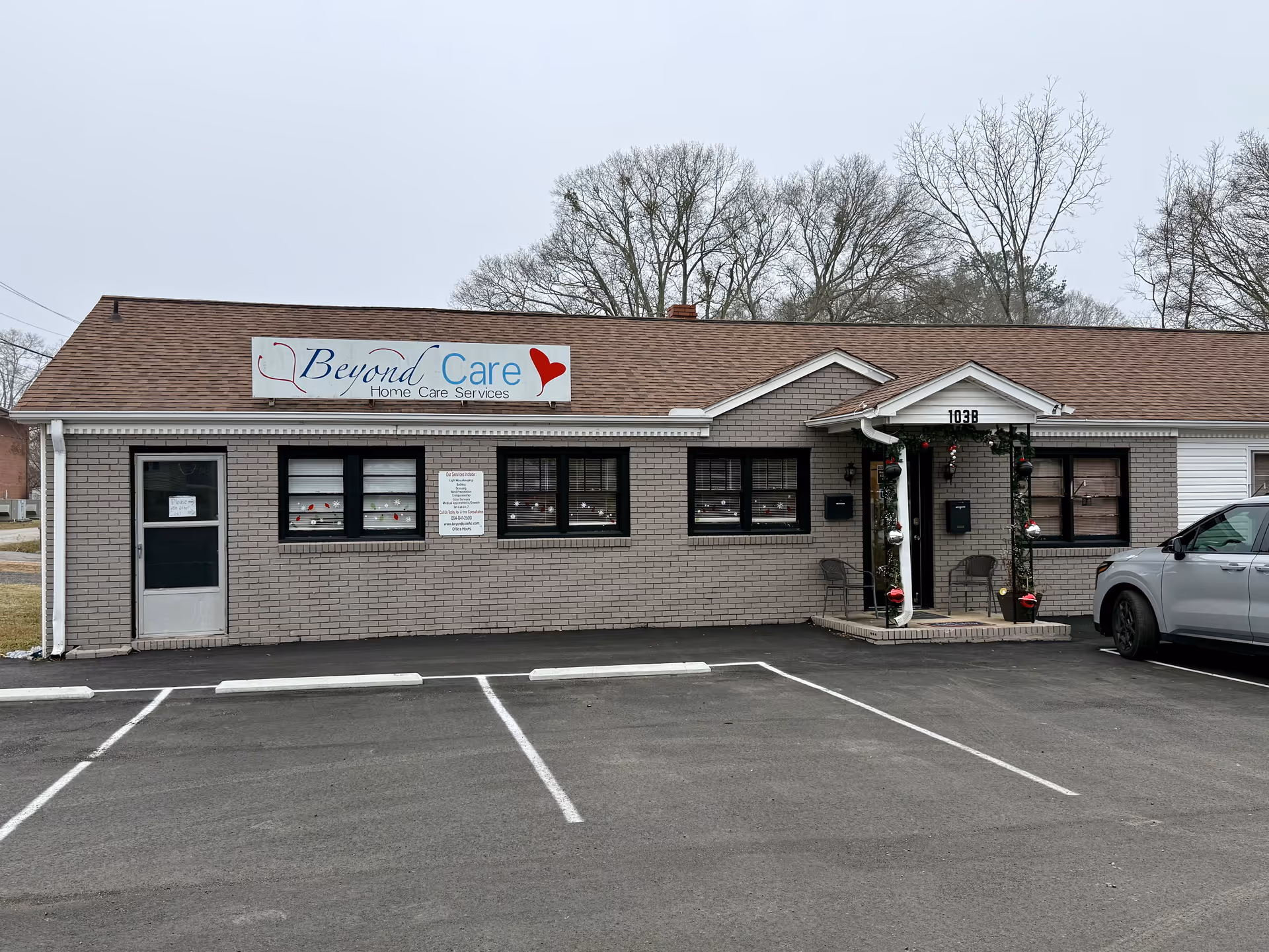 Single-story brick building with Beyond Care sign, front entrance, and a parked car.