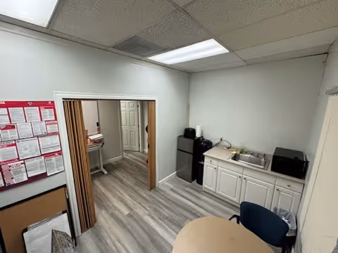 Compact, clean kitchenette in a senior facility with sink, microwave, cabinets, and table.