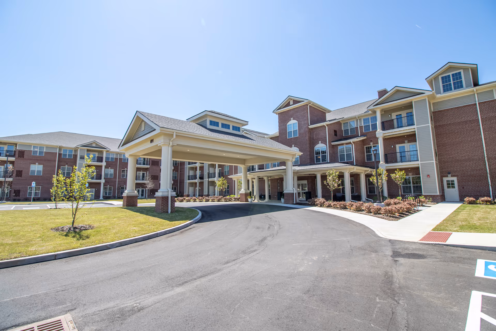 Brick senior living building with a covered entrance drive and landscaped surroundings.