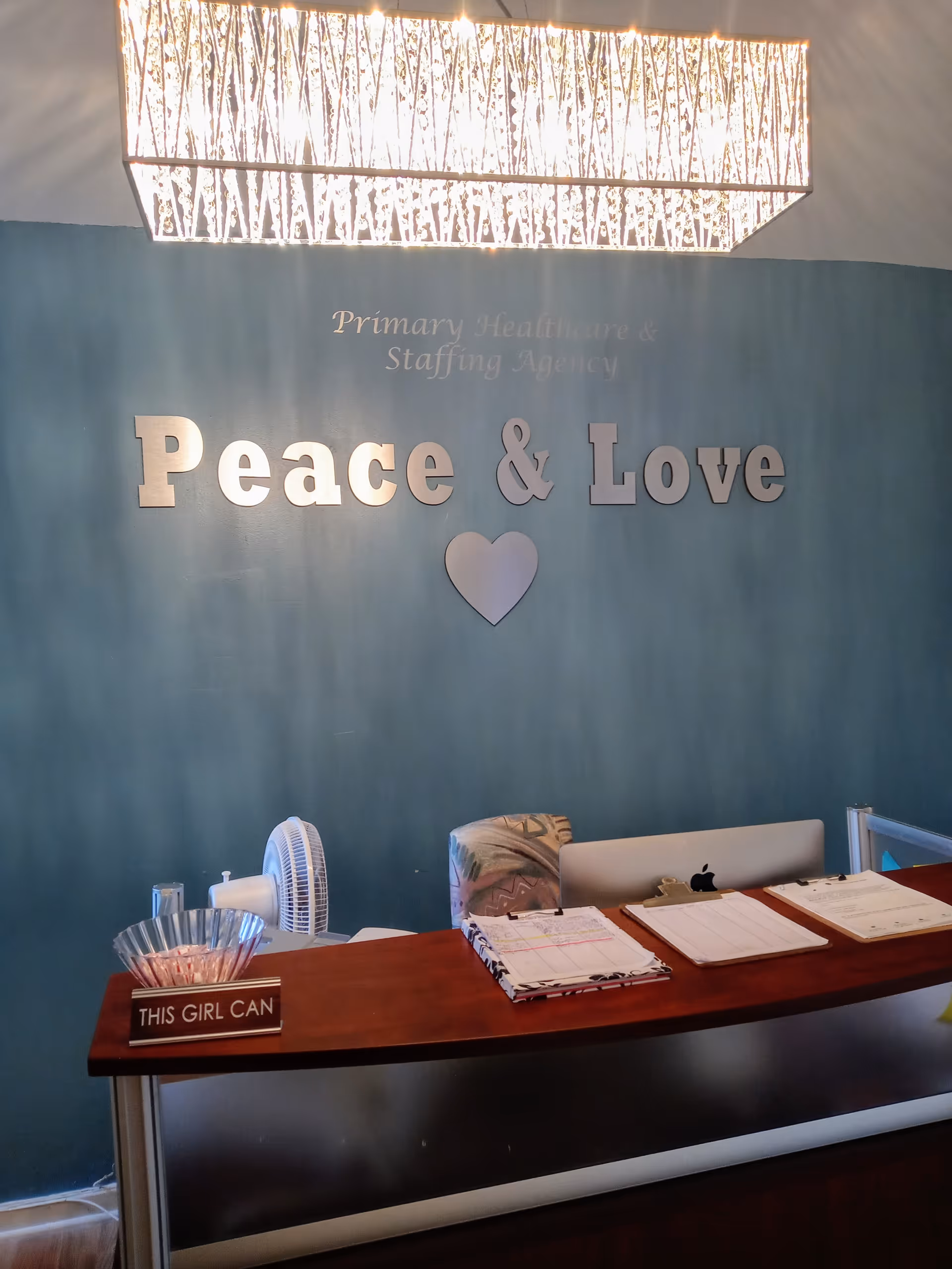 Reception desk in teal lobby featuring Peace & Love sign and heart emblem.