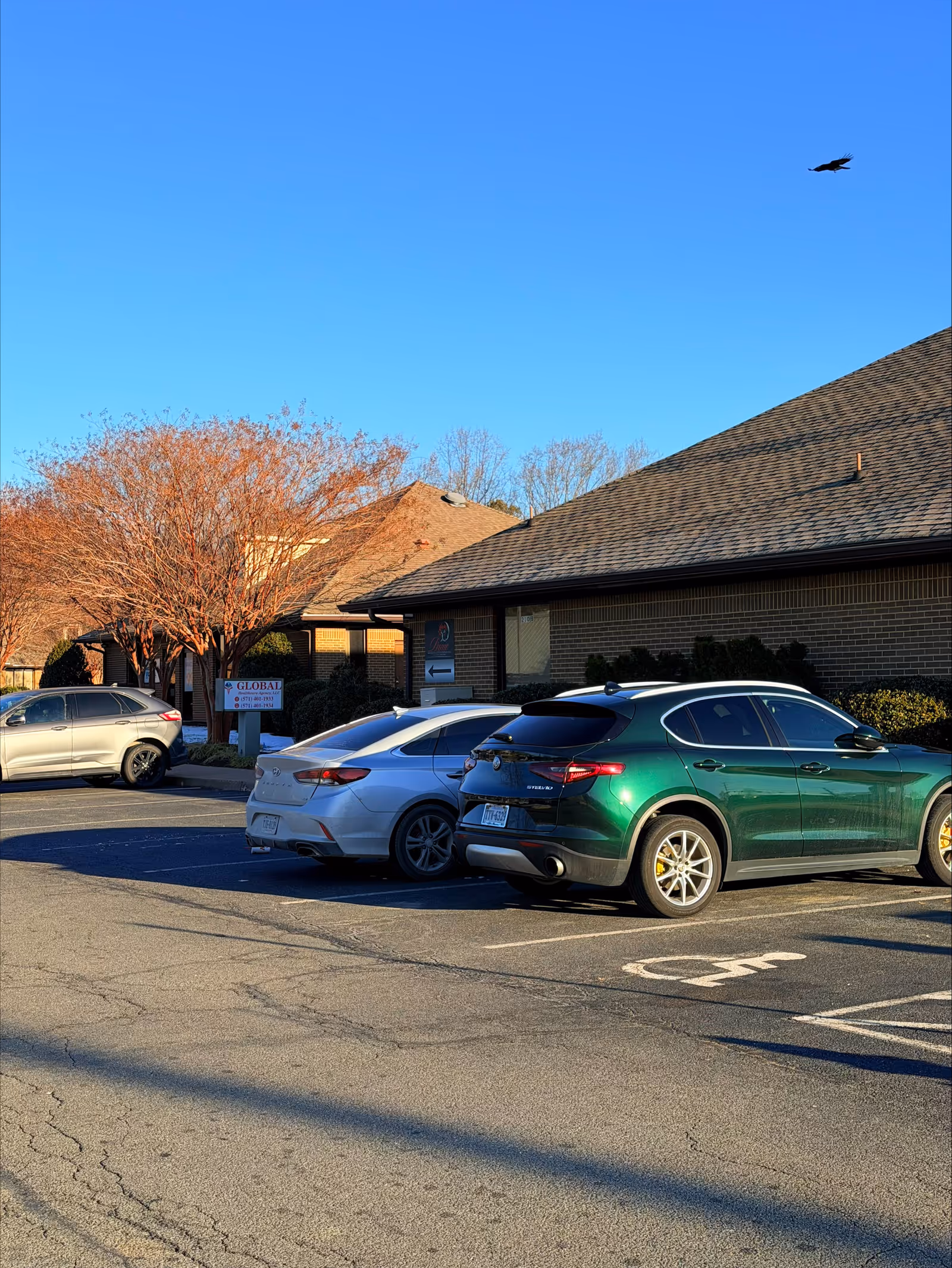 Exterior view of a brick facility with parked cars and clear blue sky.