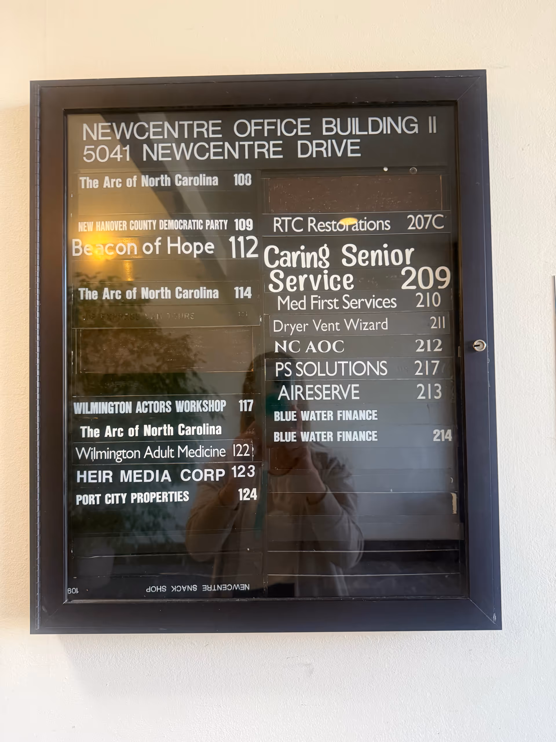 Glass directory board listing Caring Senior Service among tenants and suite numbers in a building lobby.