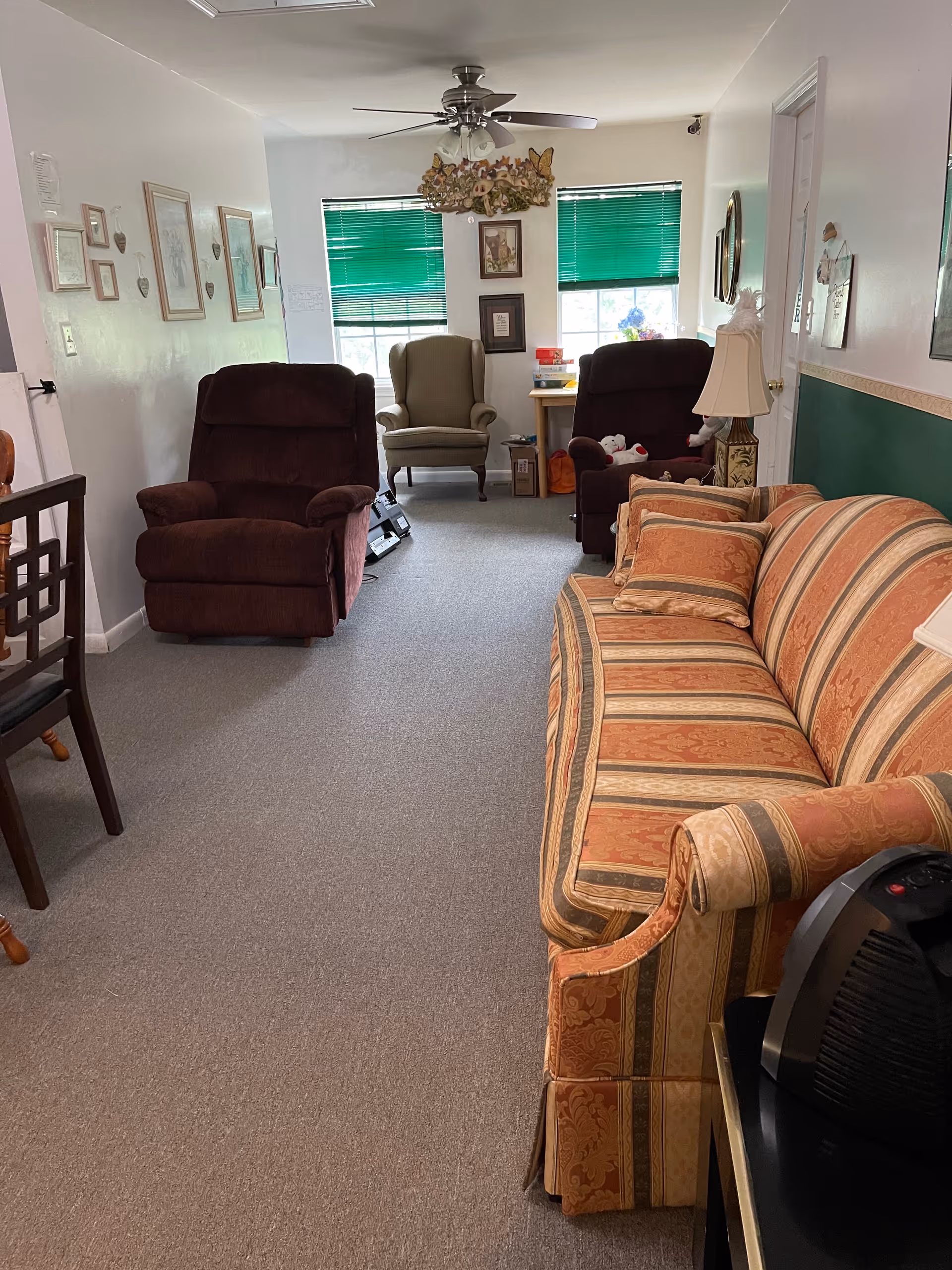 Cheryl's Place lounge with striped sofa and recliners facing large windows with green blinds.