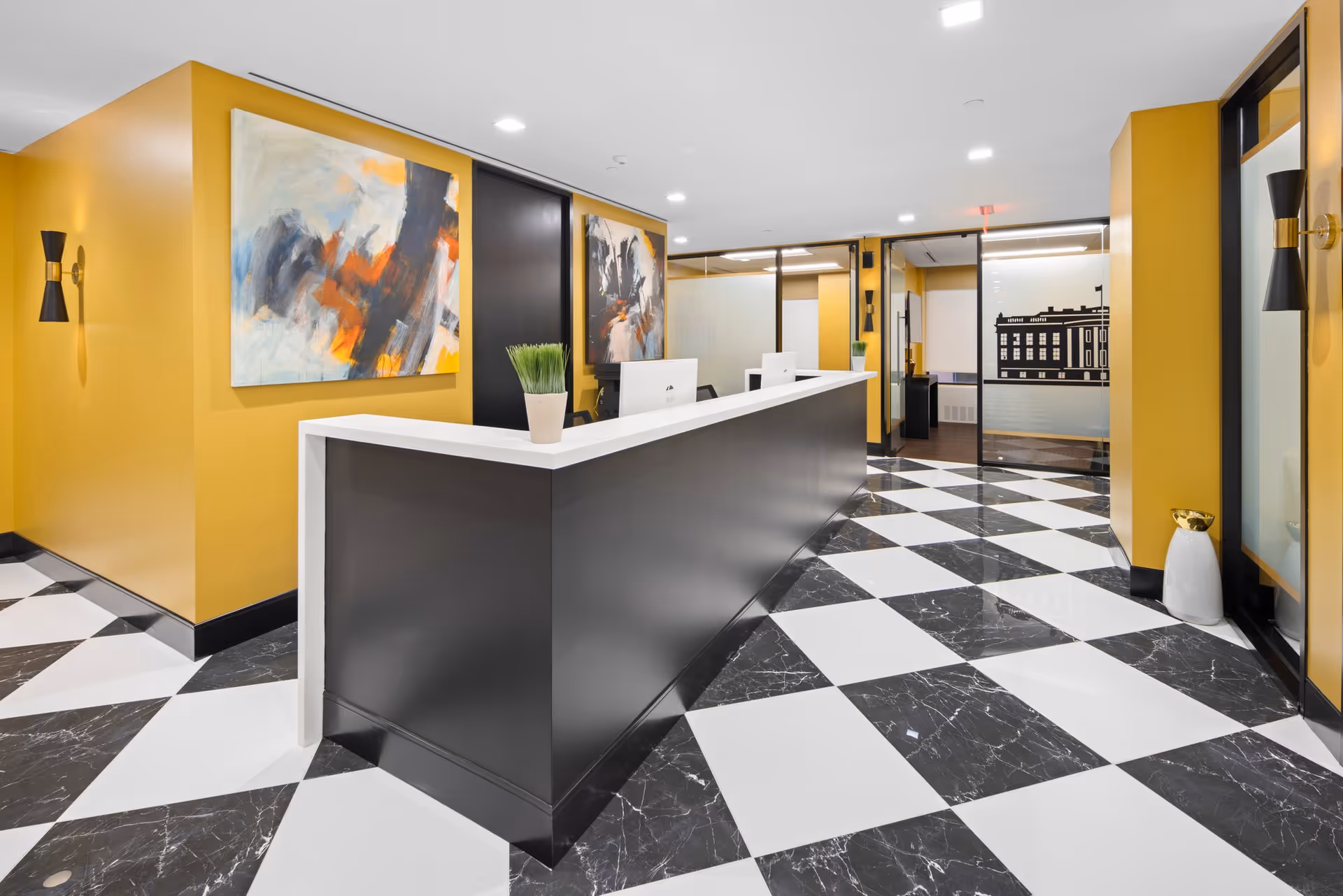 Reception desk in a yellow-walled lobby with abstract art and a checkered black-and-white floor.